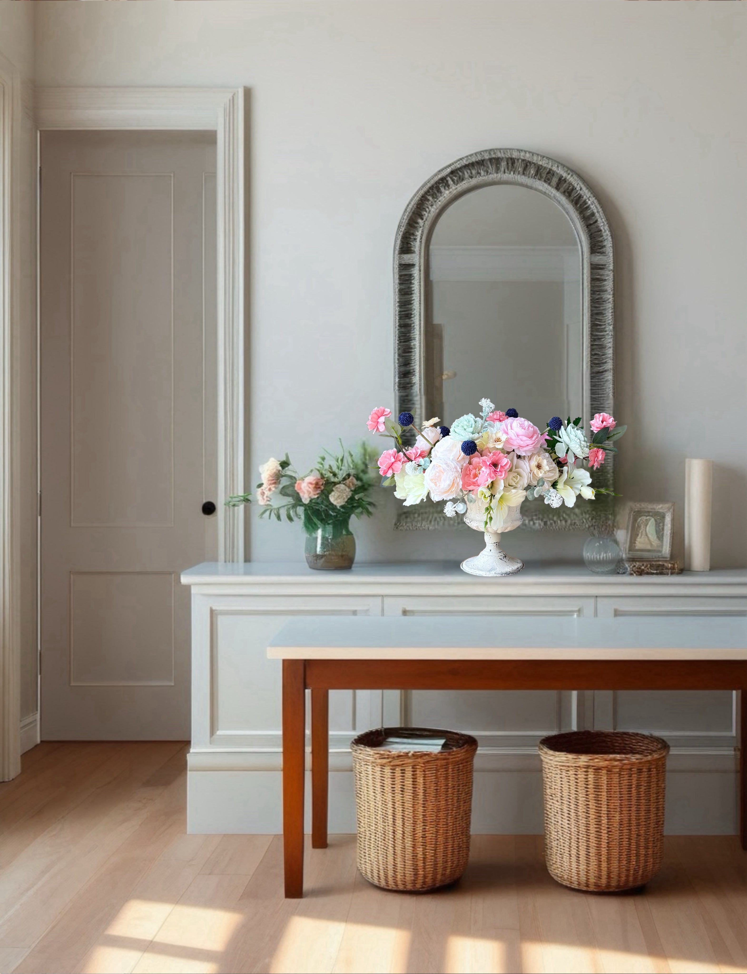 Decorative setup with a mirror, table, and floral arrangements in a room.