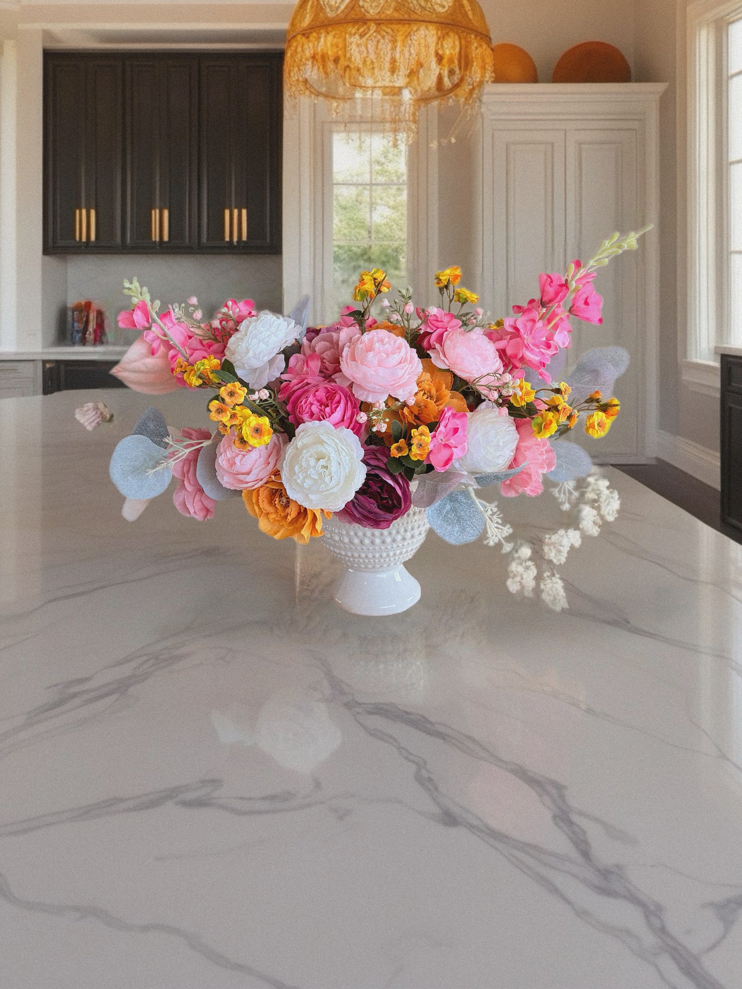 Colorful flower arrangement on a marble countertop in a kitchen.