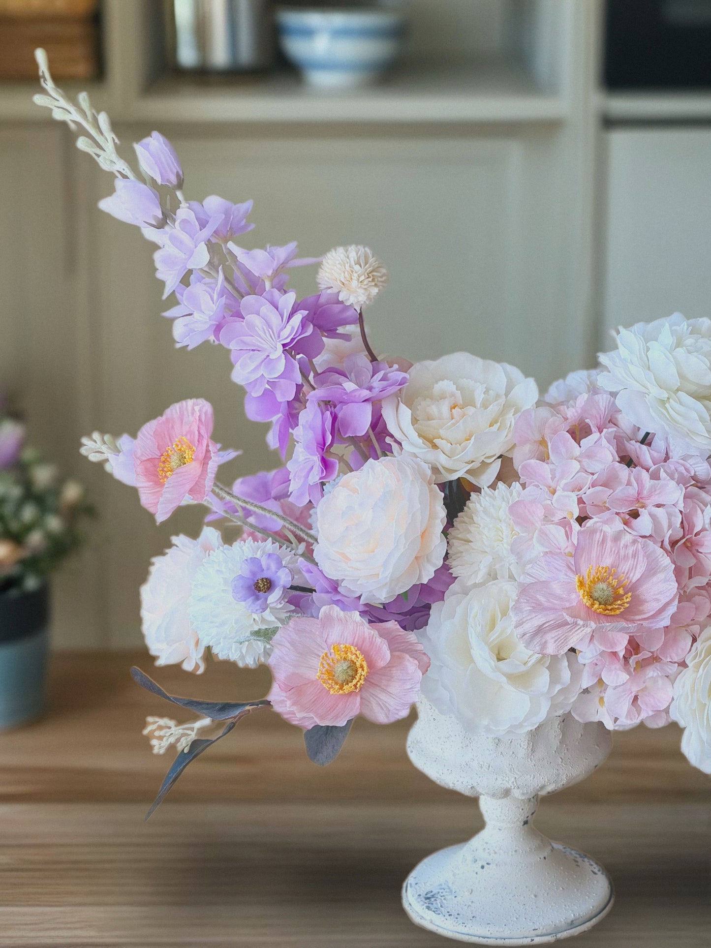 Floral arrangement in a white vase on a wooden surface with a blurred background