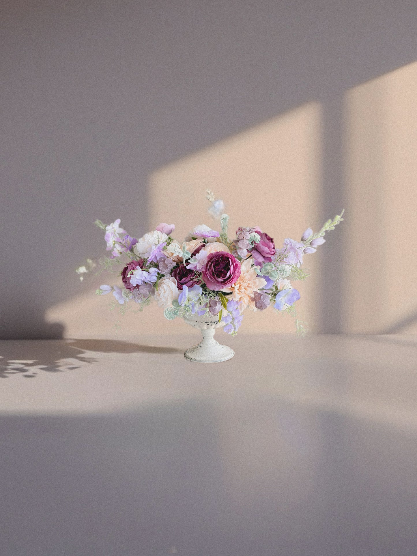Floral arrangement on a white pedestal against a neutral background