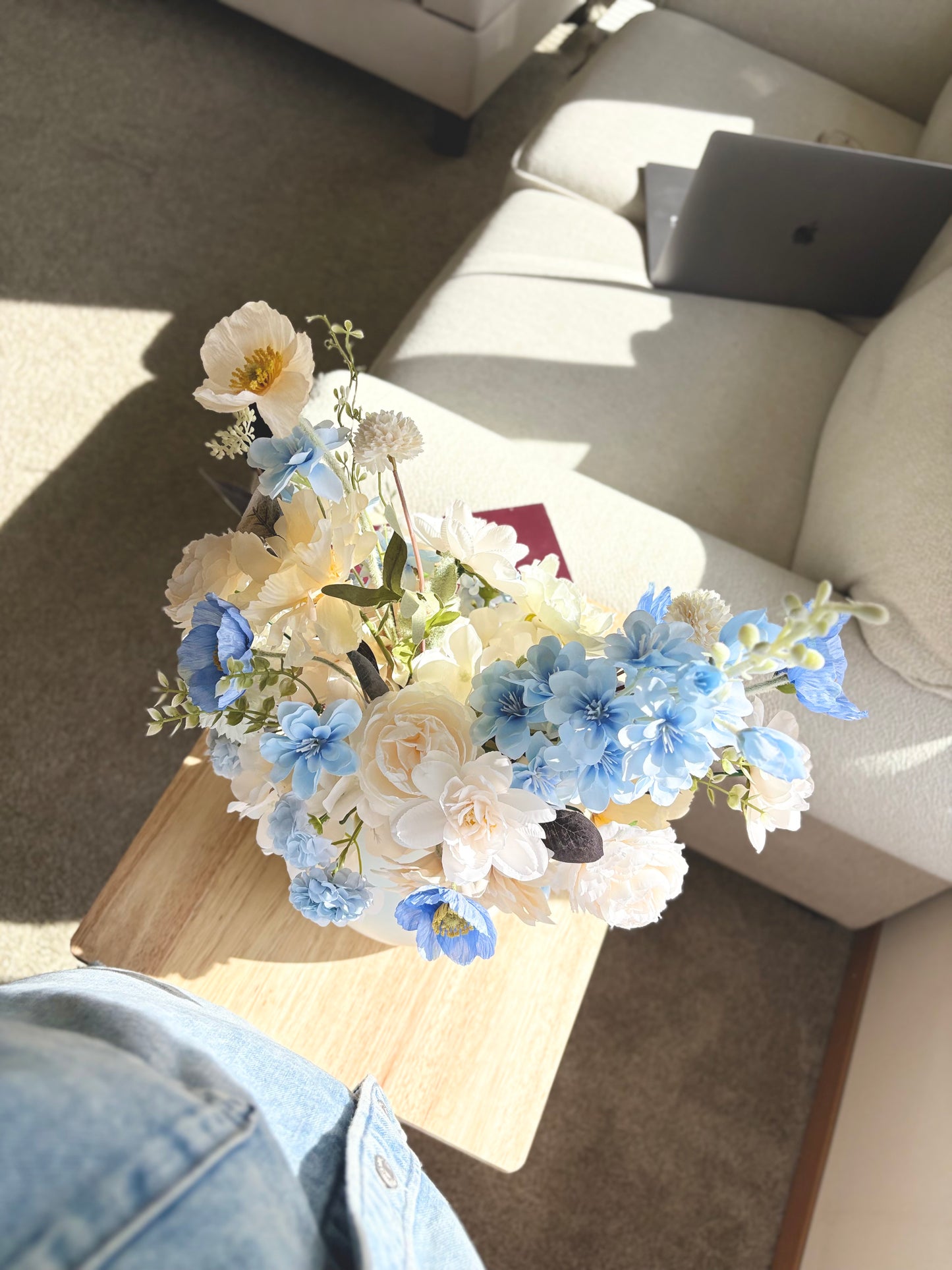 Floral arrangement on a coffee table with a laptop in the background