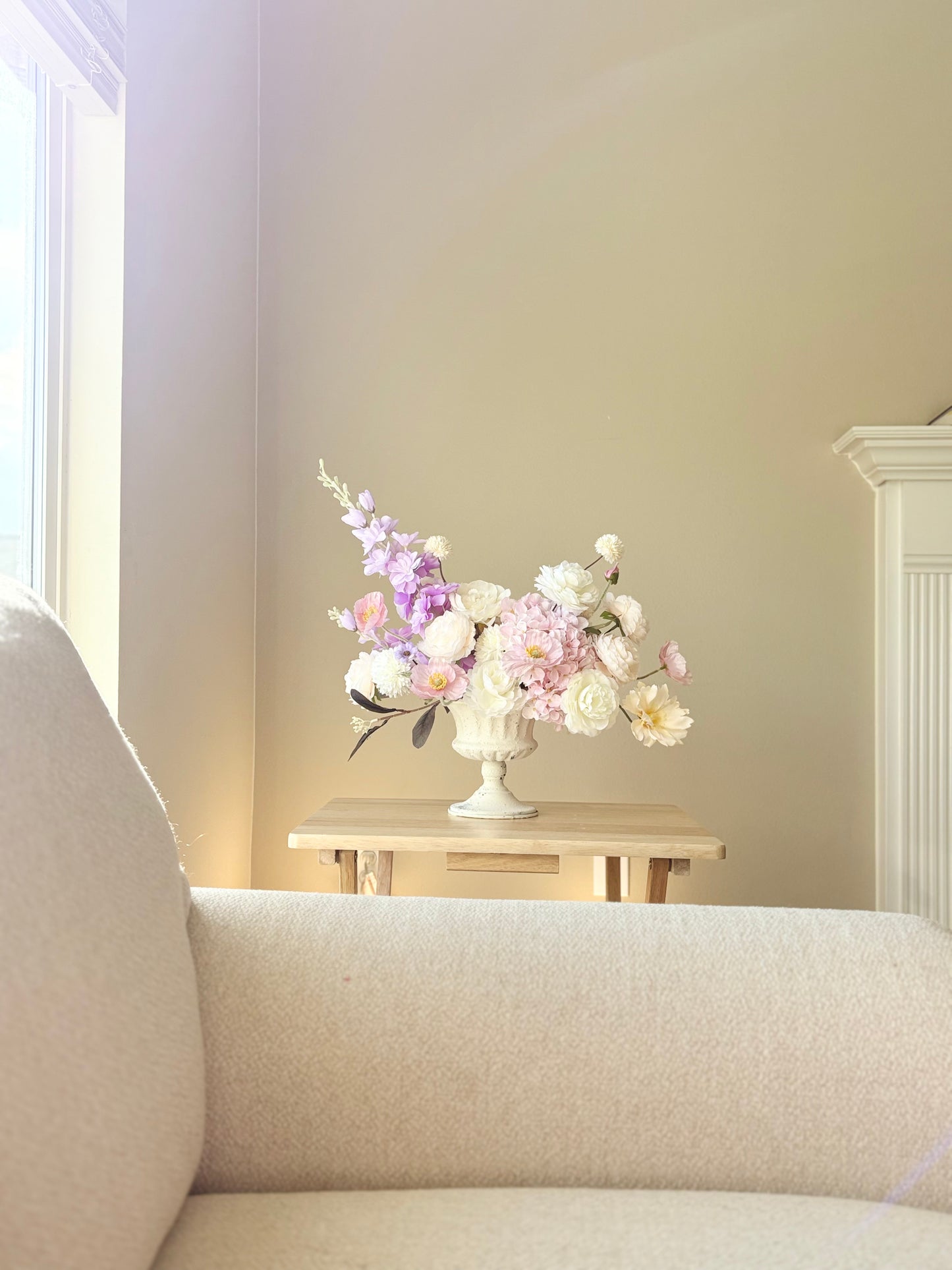 Floral arrangement in a white vase on a table next to a beige sofa.