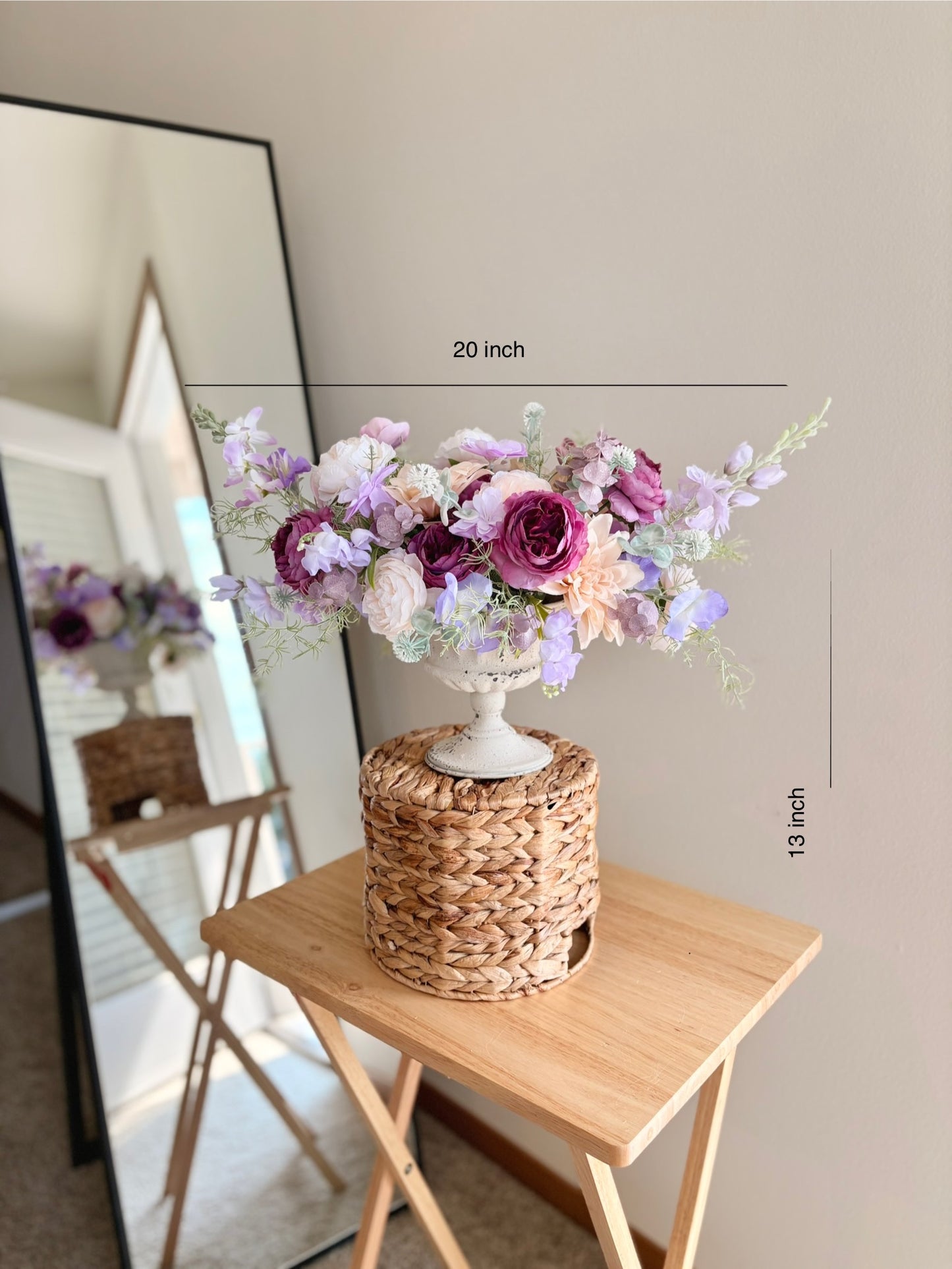 Floral arrangement on a woven stand with dimensions indicated, placed on a wooden table.