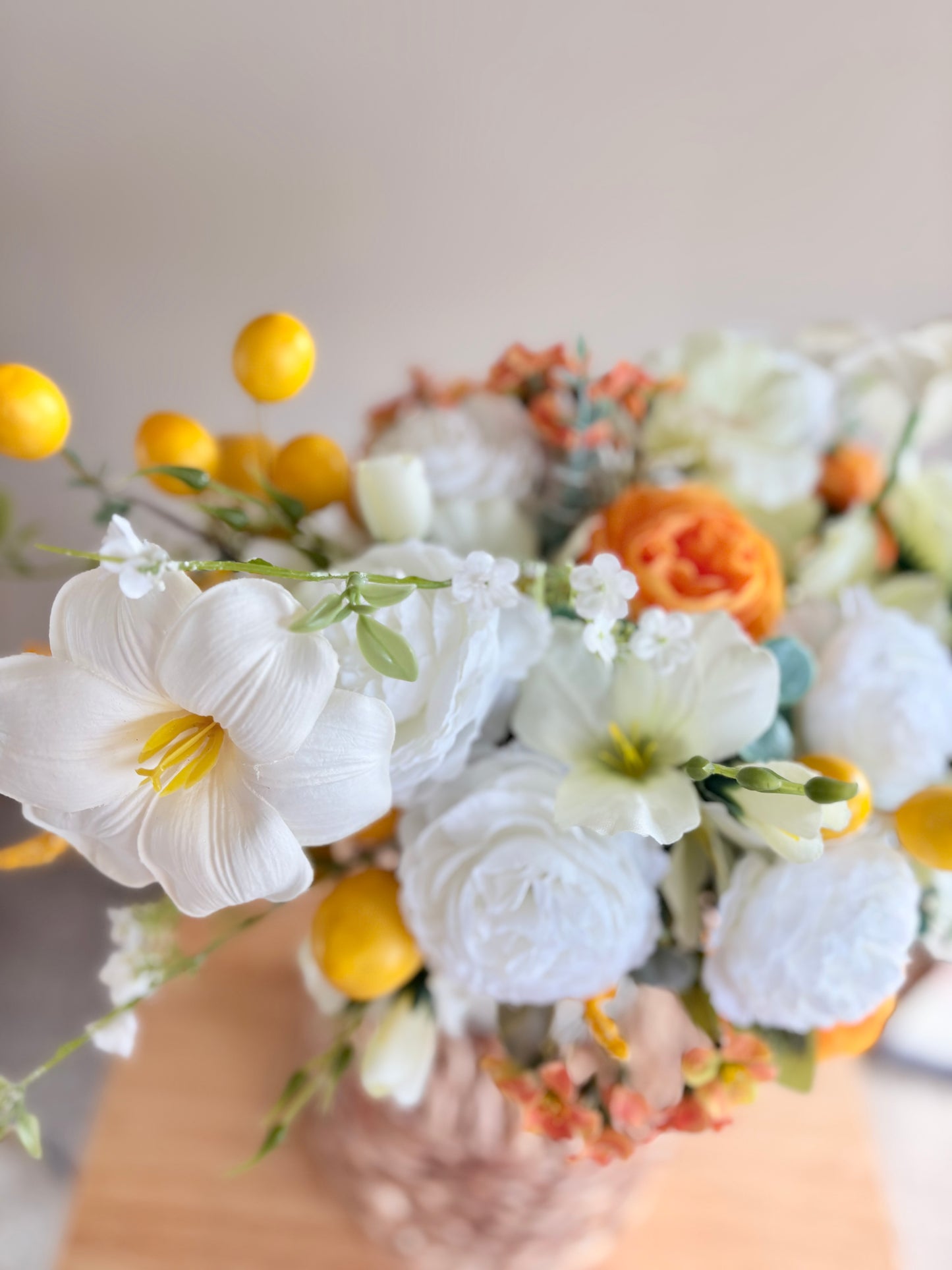 Bouquet of flowers with white, yellow, and orange flowers on a neutral background