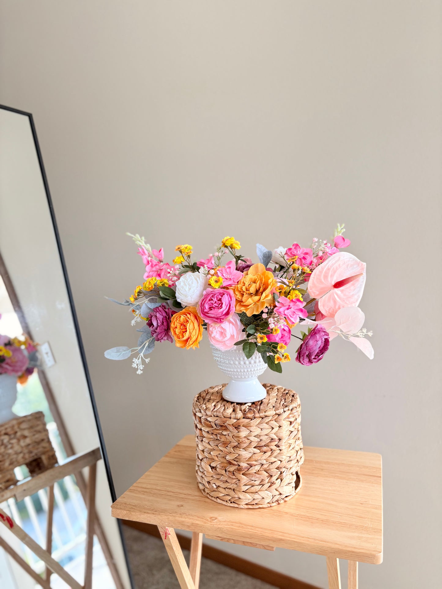 Bouquet of flowers in a woven basket on a wooden table with a neutral background