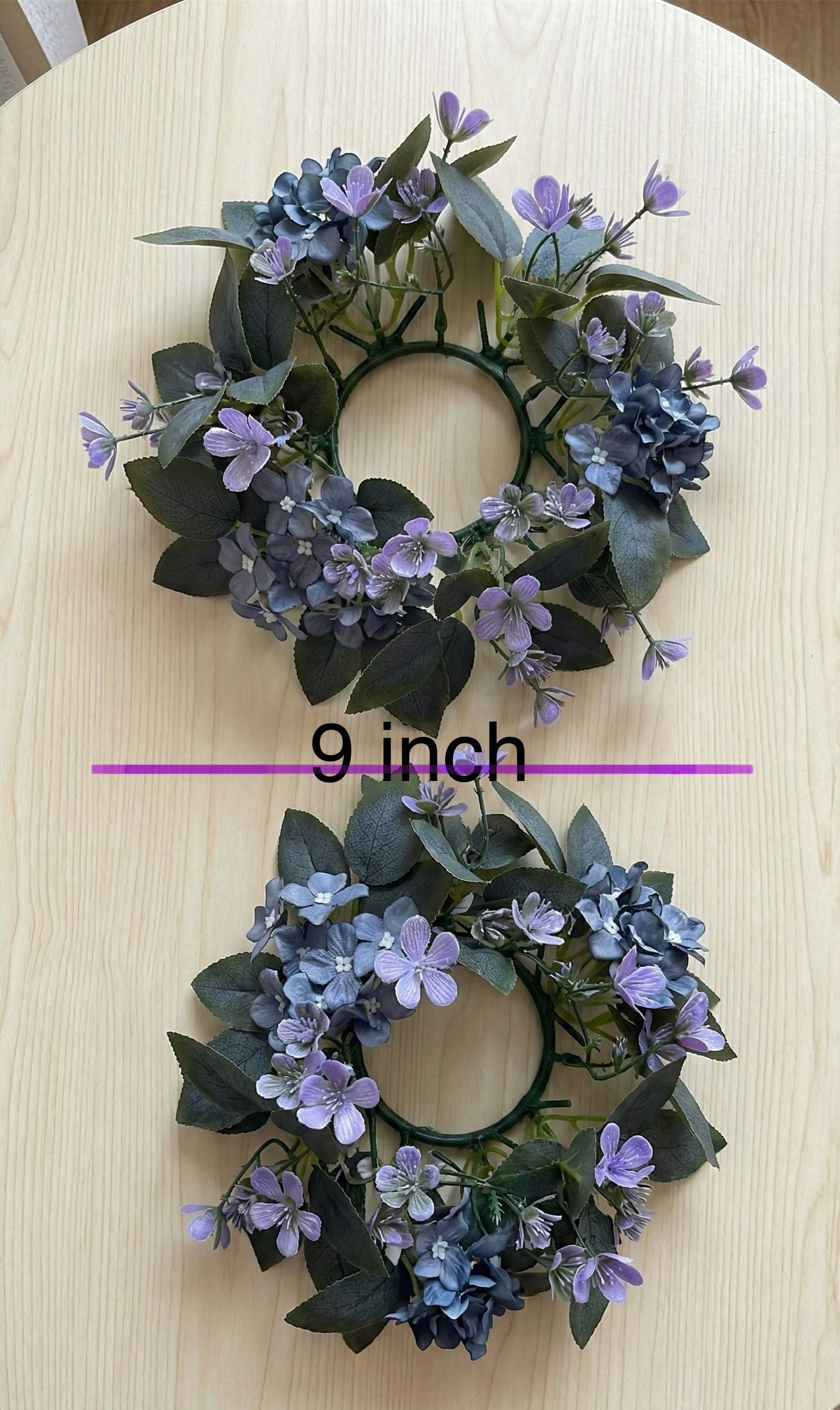Two 9-inch artificial flower wreaths on a wooden surface.