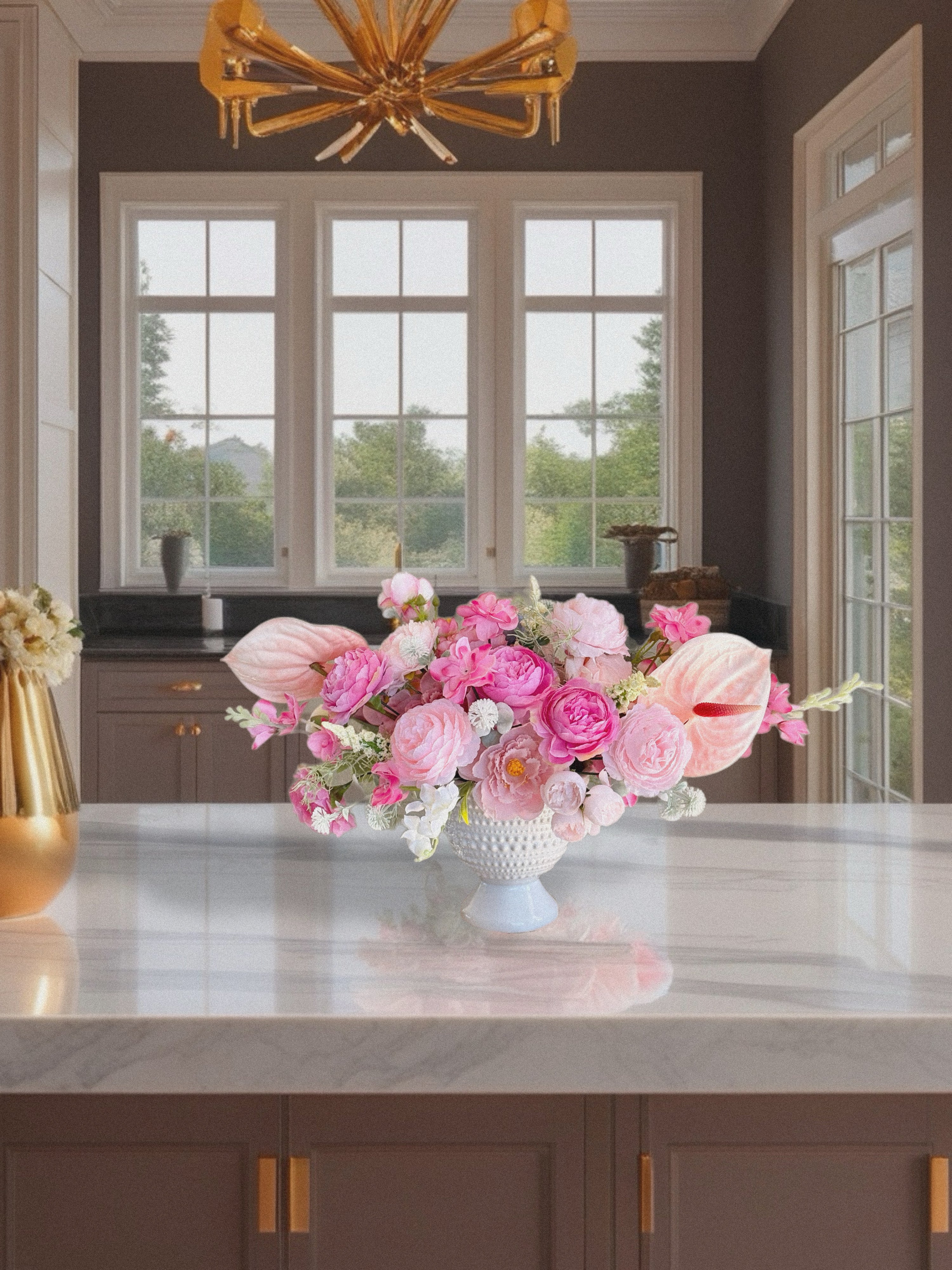 Floral arrangement on a kitchen counter with a chandelier above