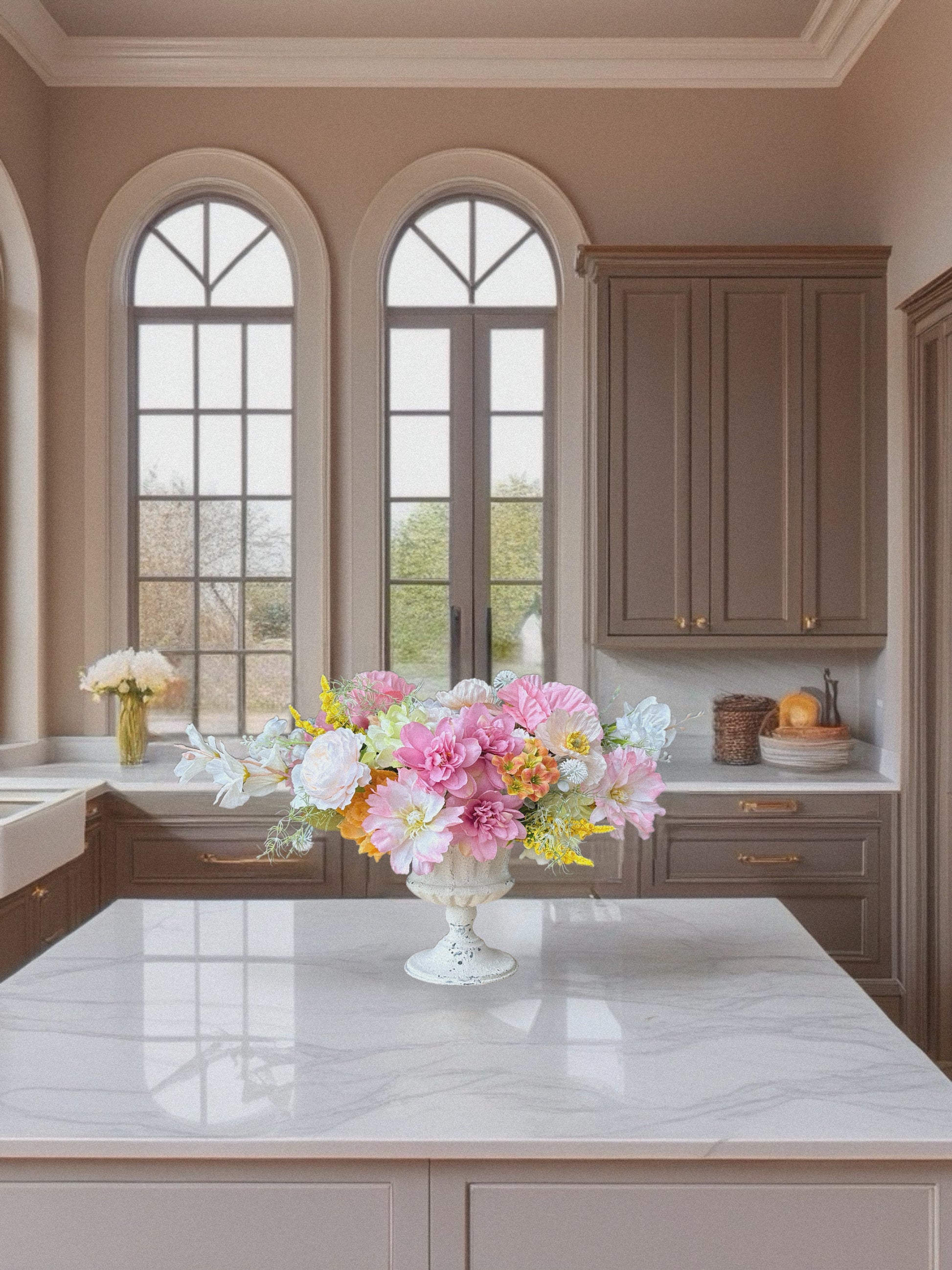 Modern kitchen with marble island, cabinets, and decorative flowers.