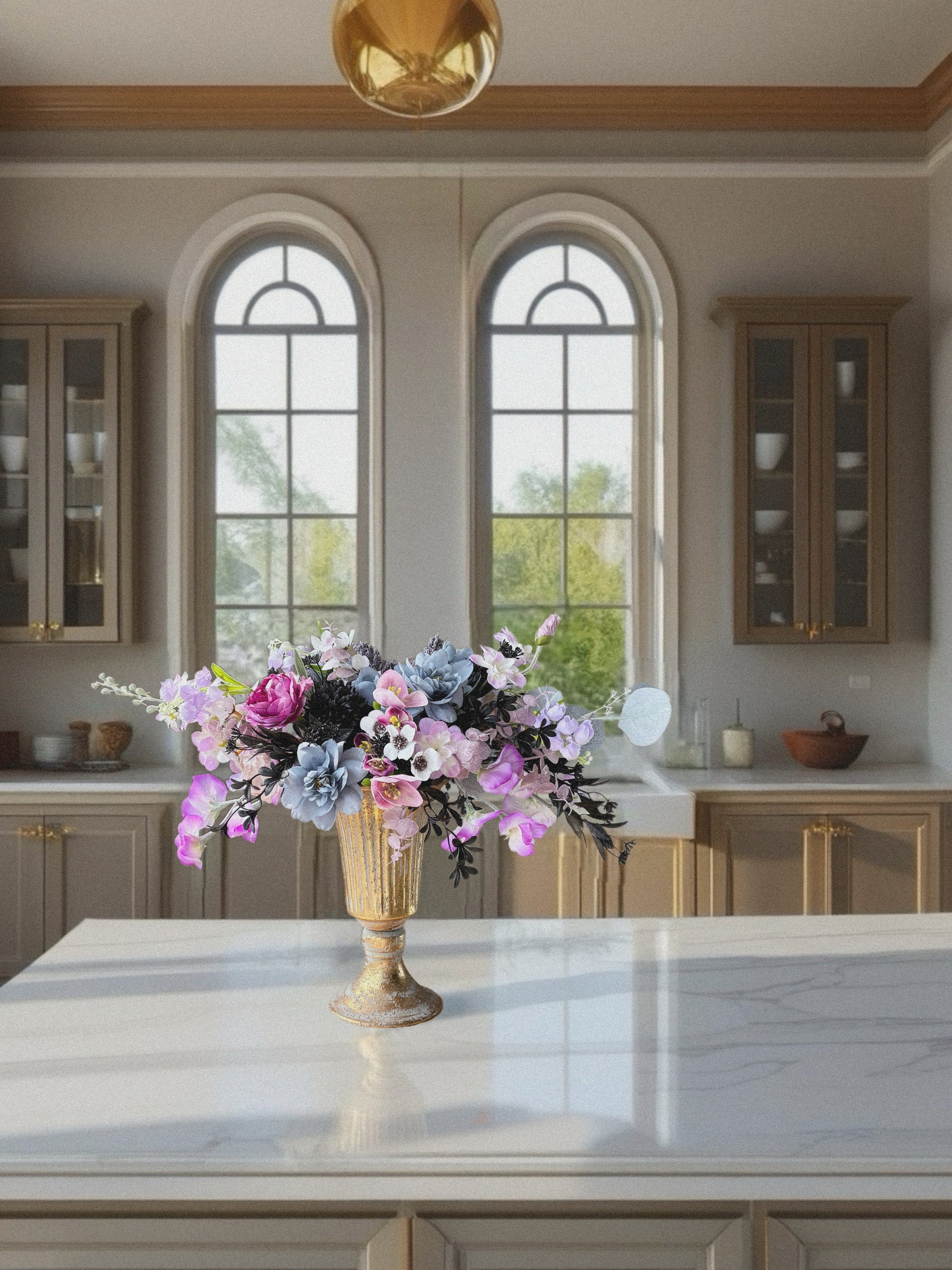 Decorative floral arrangement in a kitchen with large windows and wooden cabinets.
