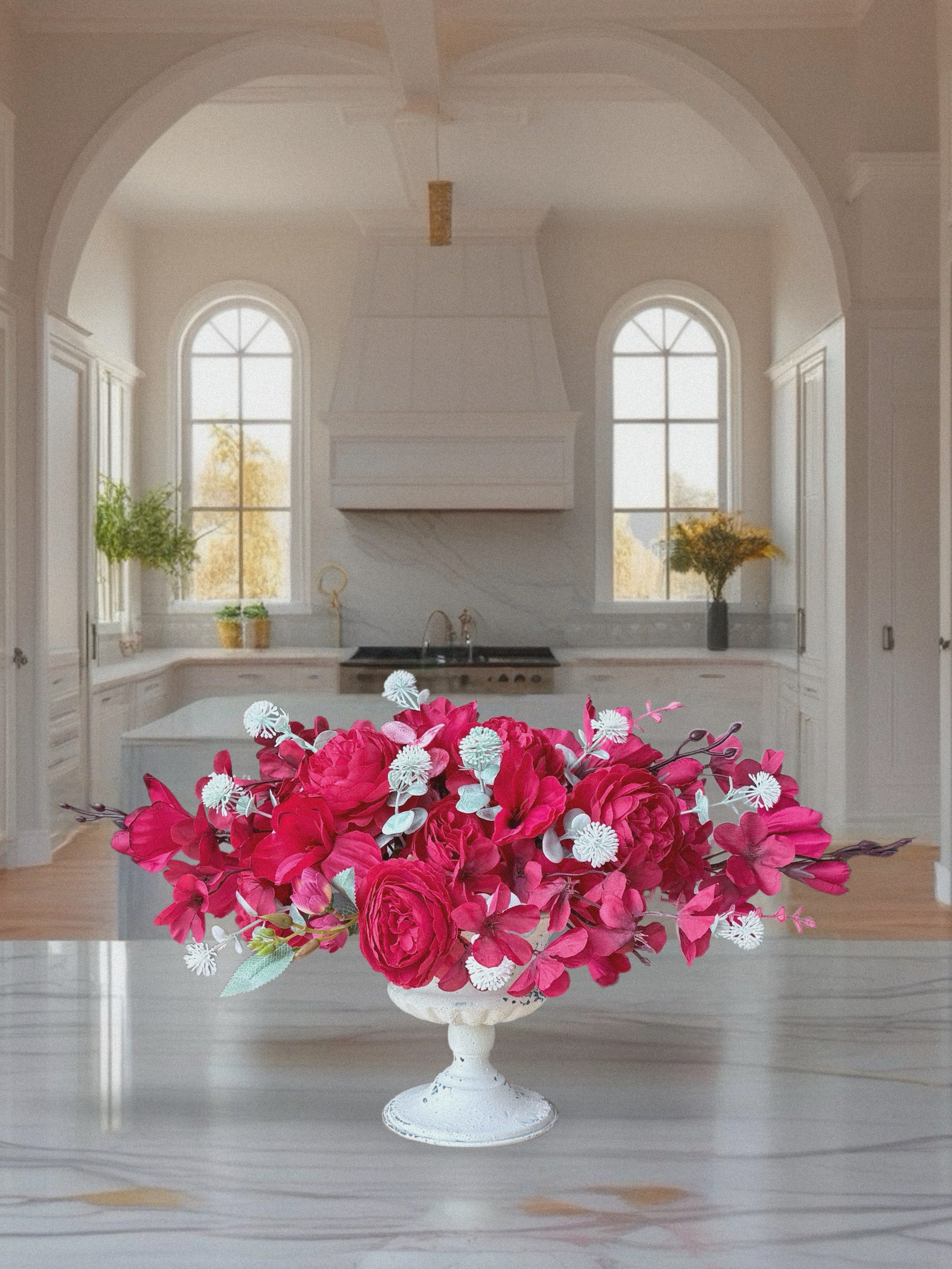 Floral arrangement in a white vase on a kitchen counter with a bright and airy kitchen in the background.