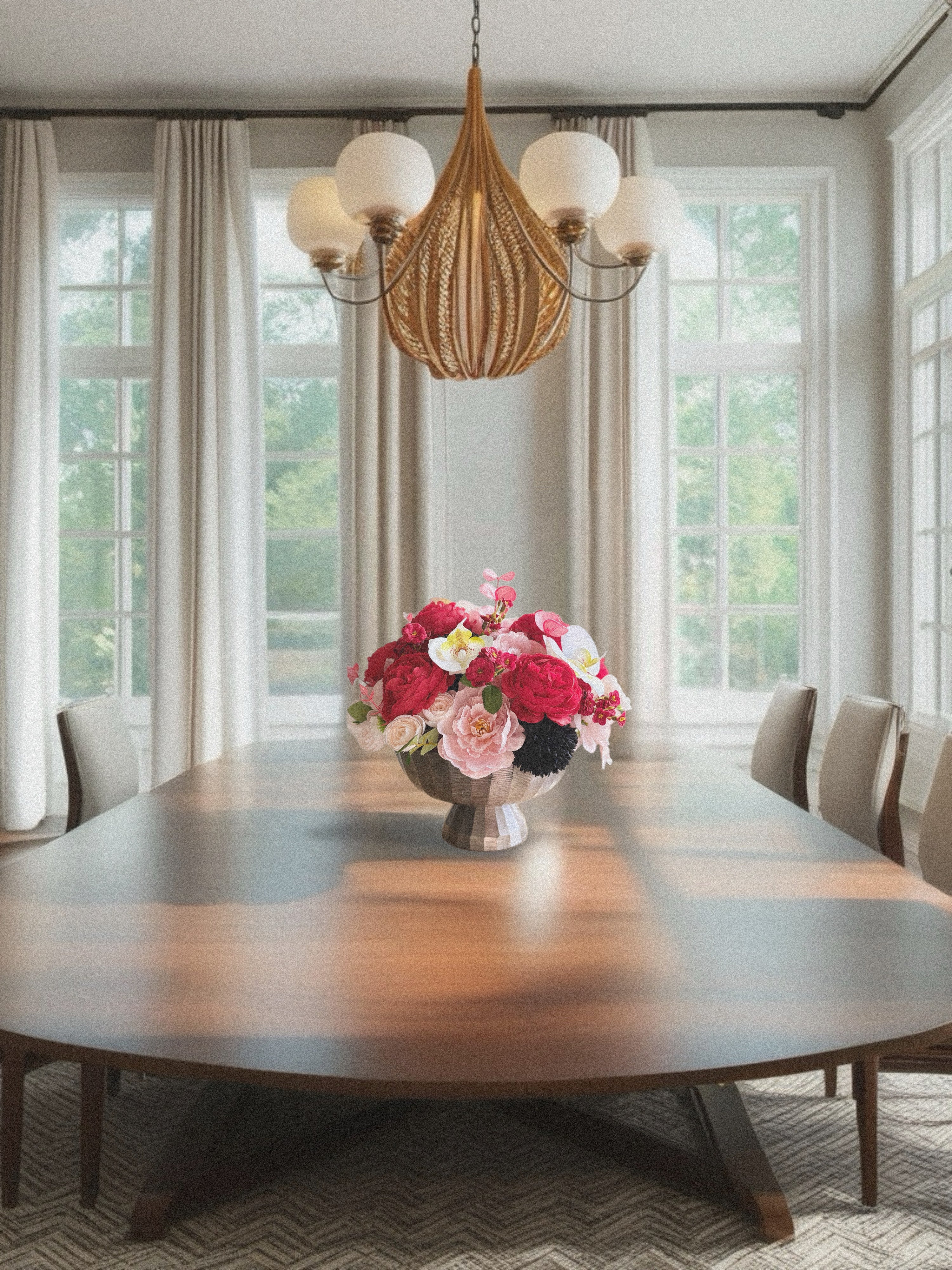 Dining room with a wooden table, floral centerpiece, and wicker chandelier.