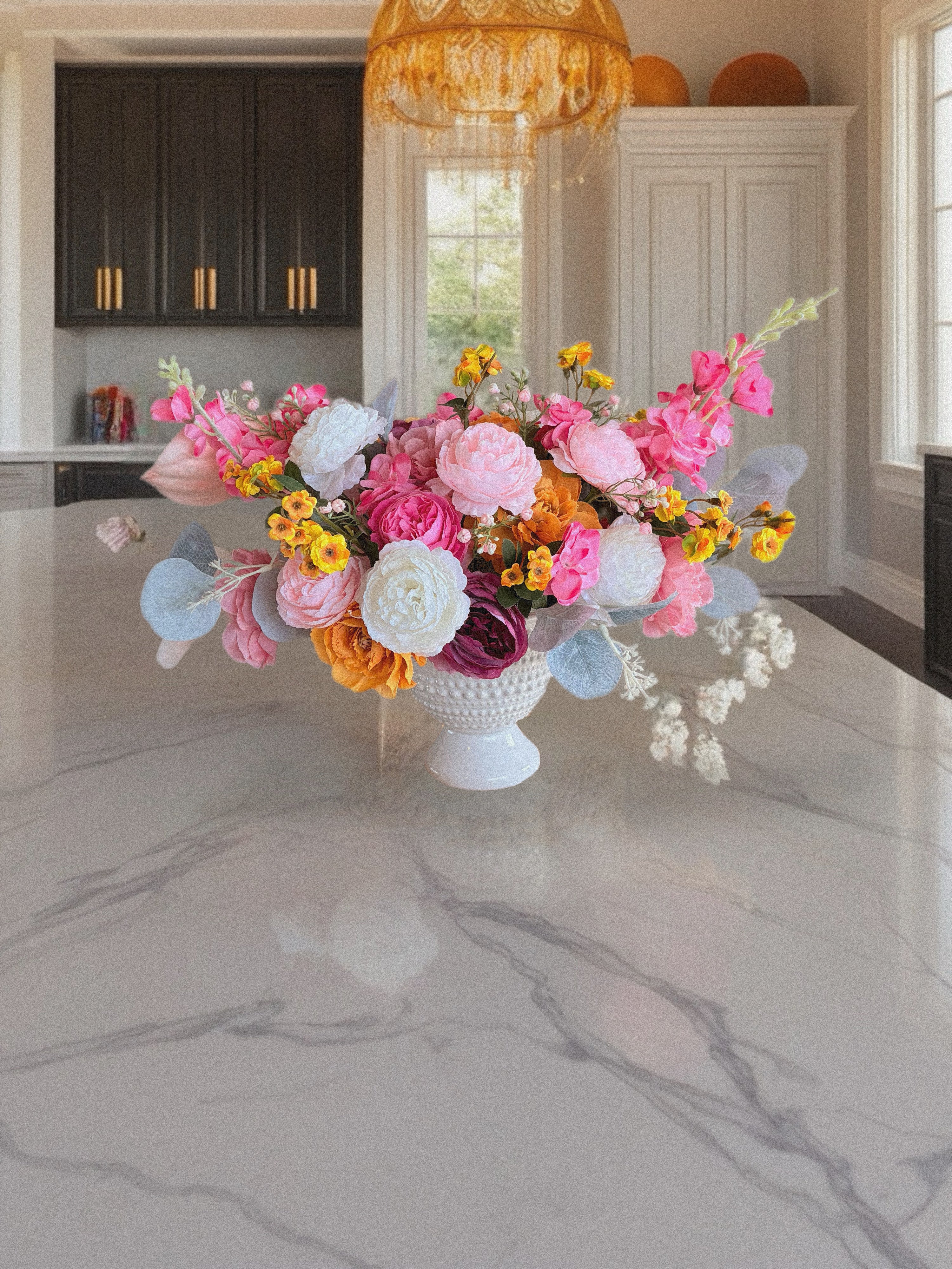 Colorful flower arrangement on a marble countertop in a kitchen.