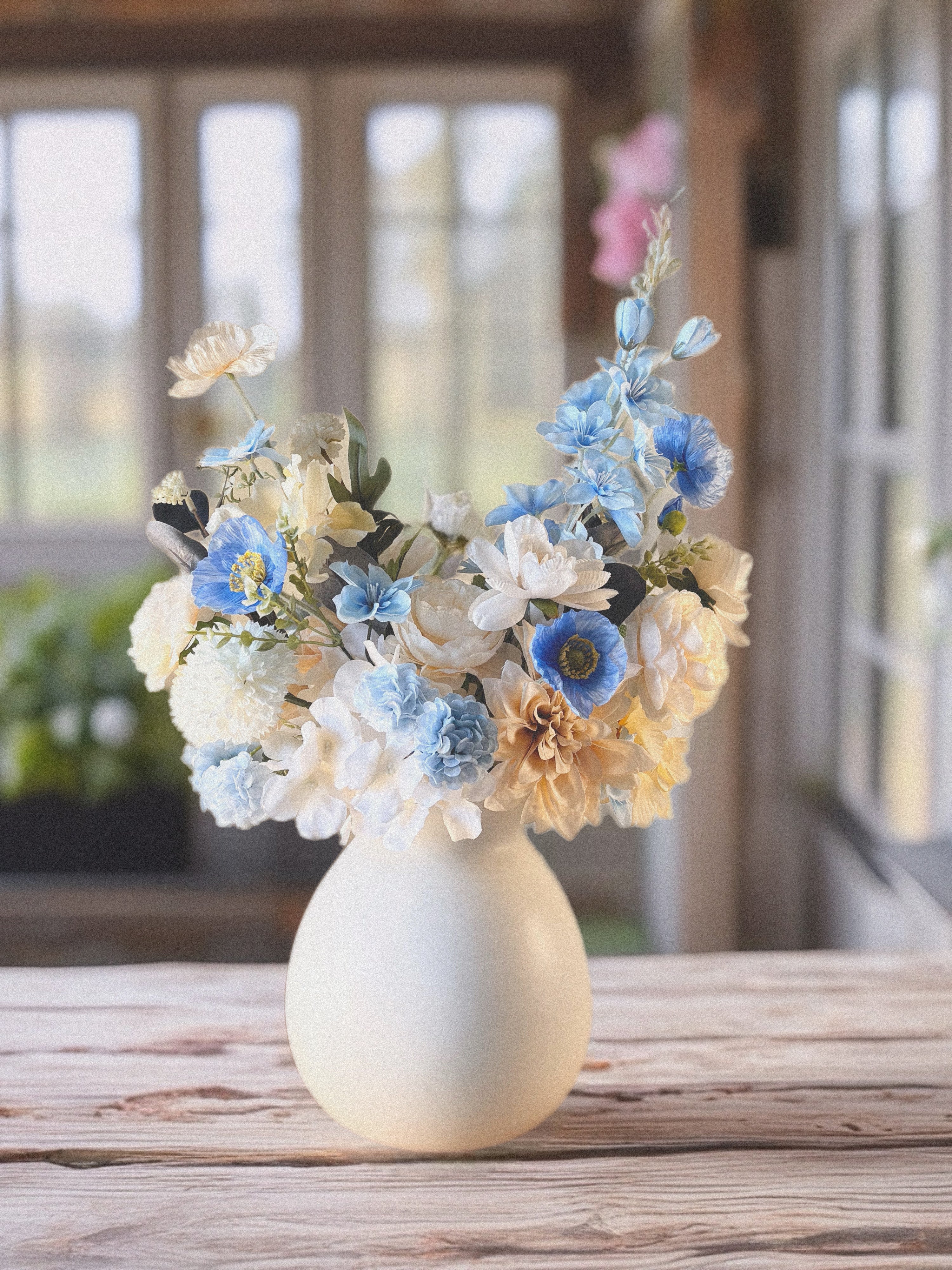 White vase with a bouquet of flowers on a wooden surface