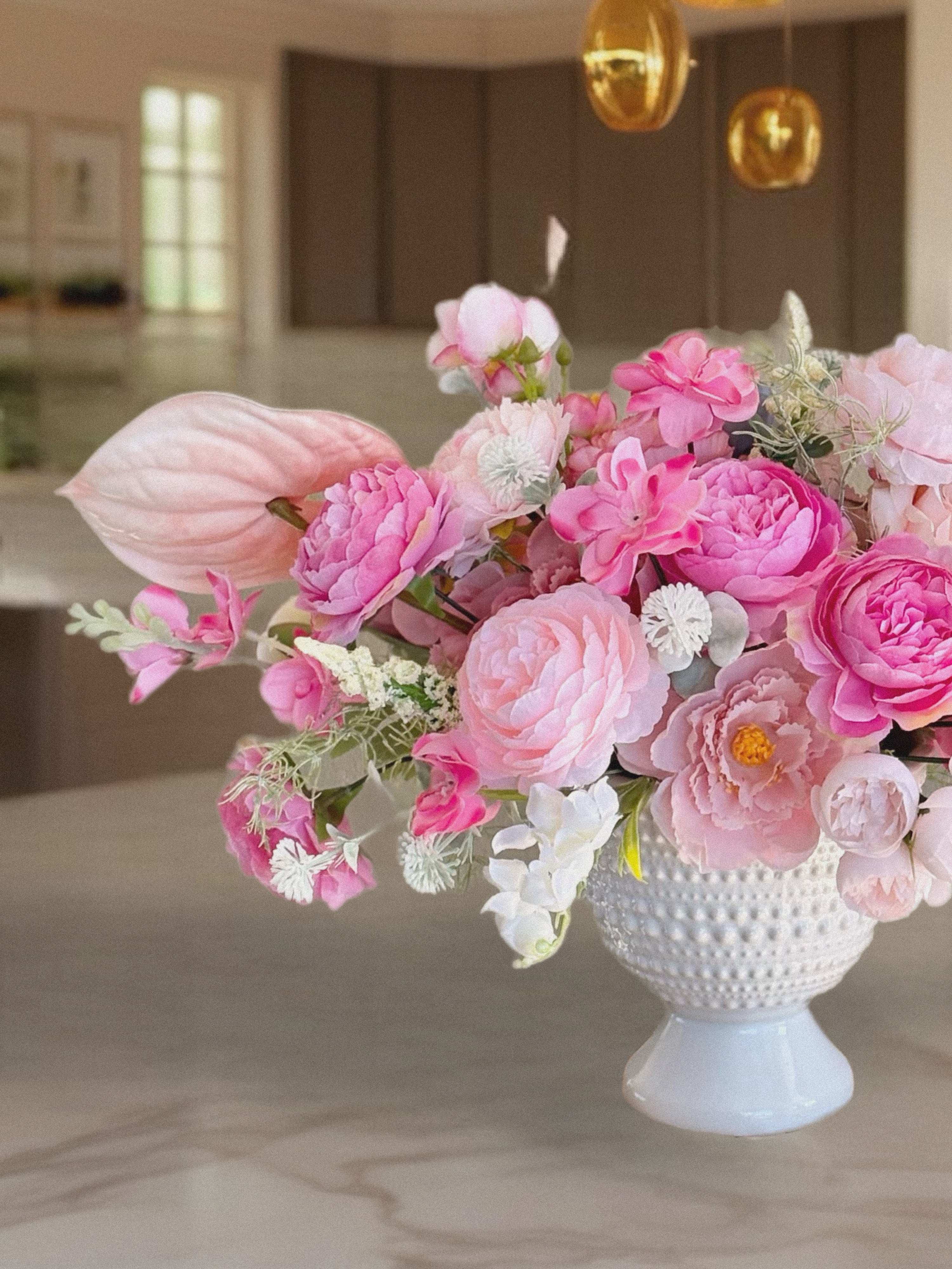 Bouquet of pink flowers in a white vase on a marble surface
