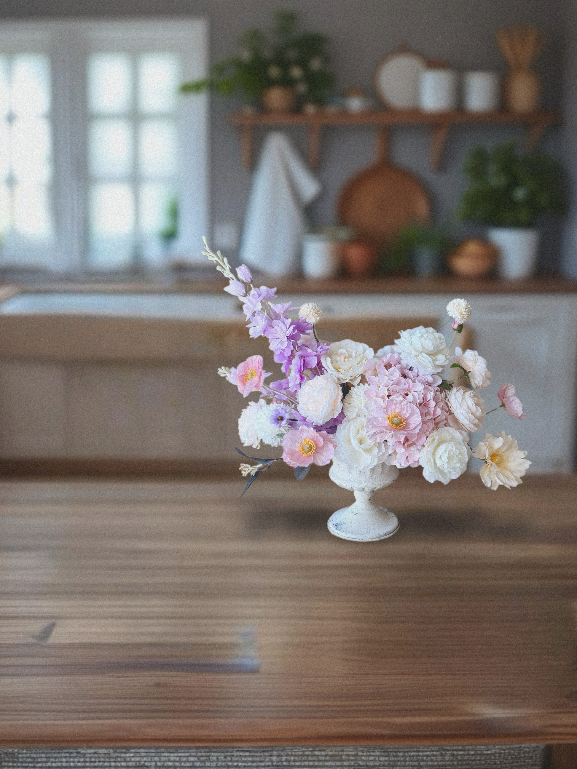 Floral arrangement in a white vase on a wooden table with a blurred background