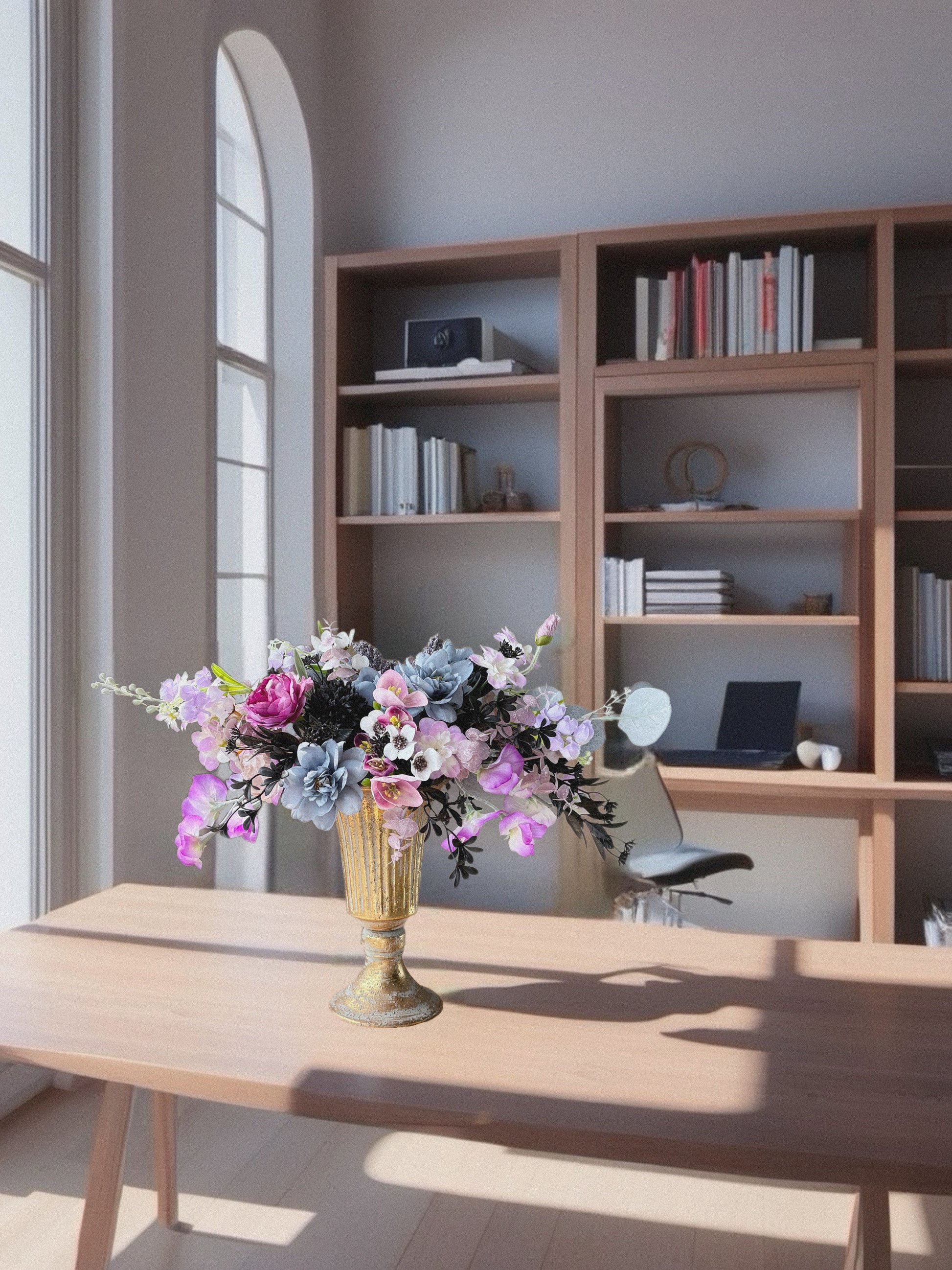 Home office with wooden desk, bookshelf, and floral arrangement