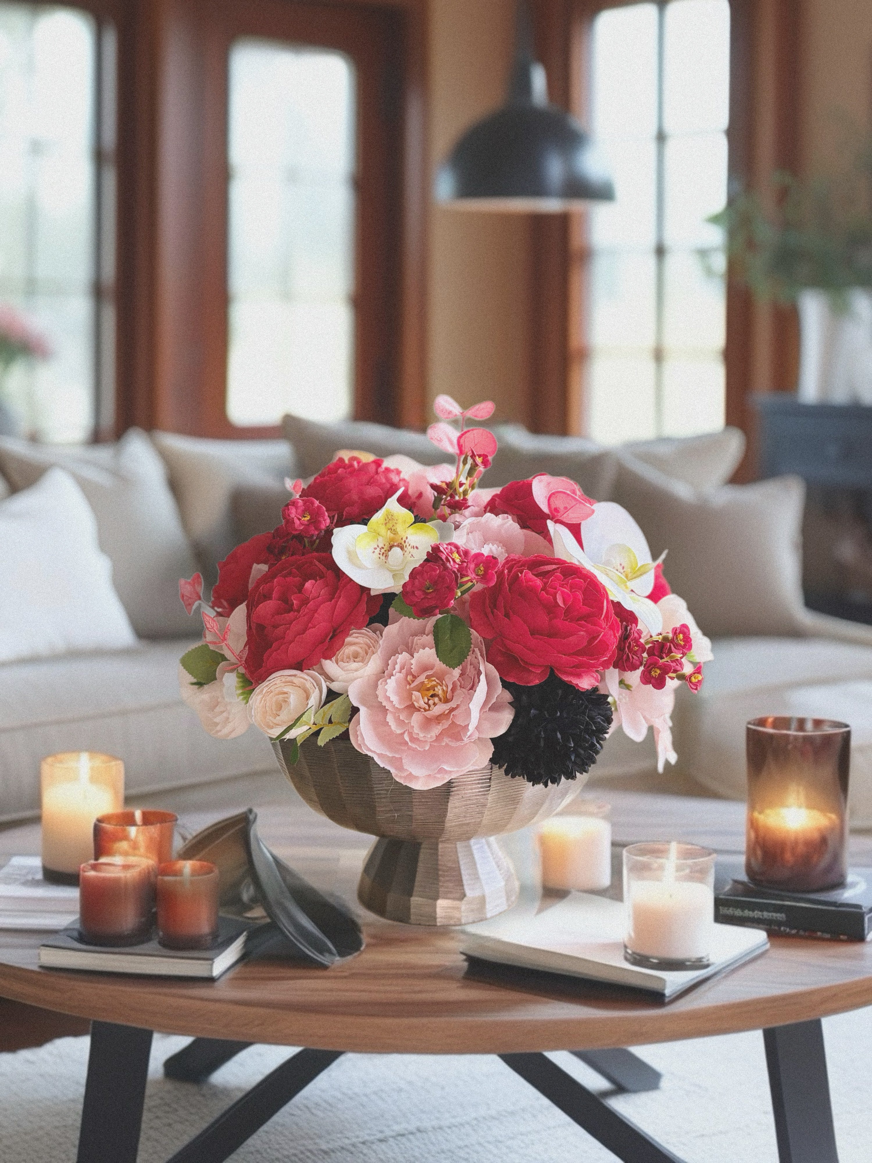 Floral arrangement on a coffee table with candles in a living room setting