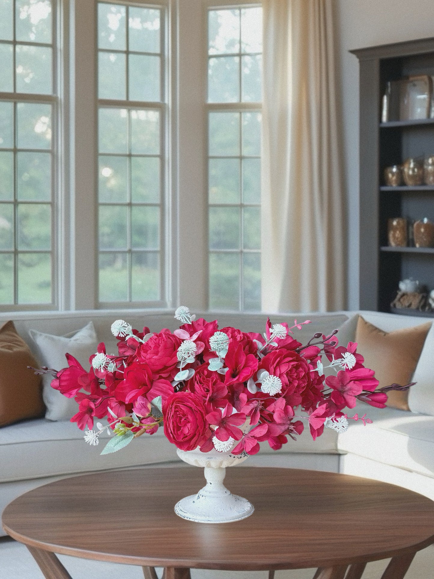 Floral arrangement in a white vase on a wooden table in a living room.