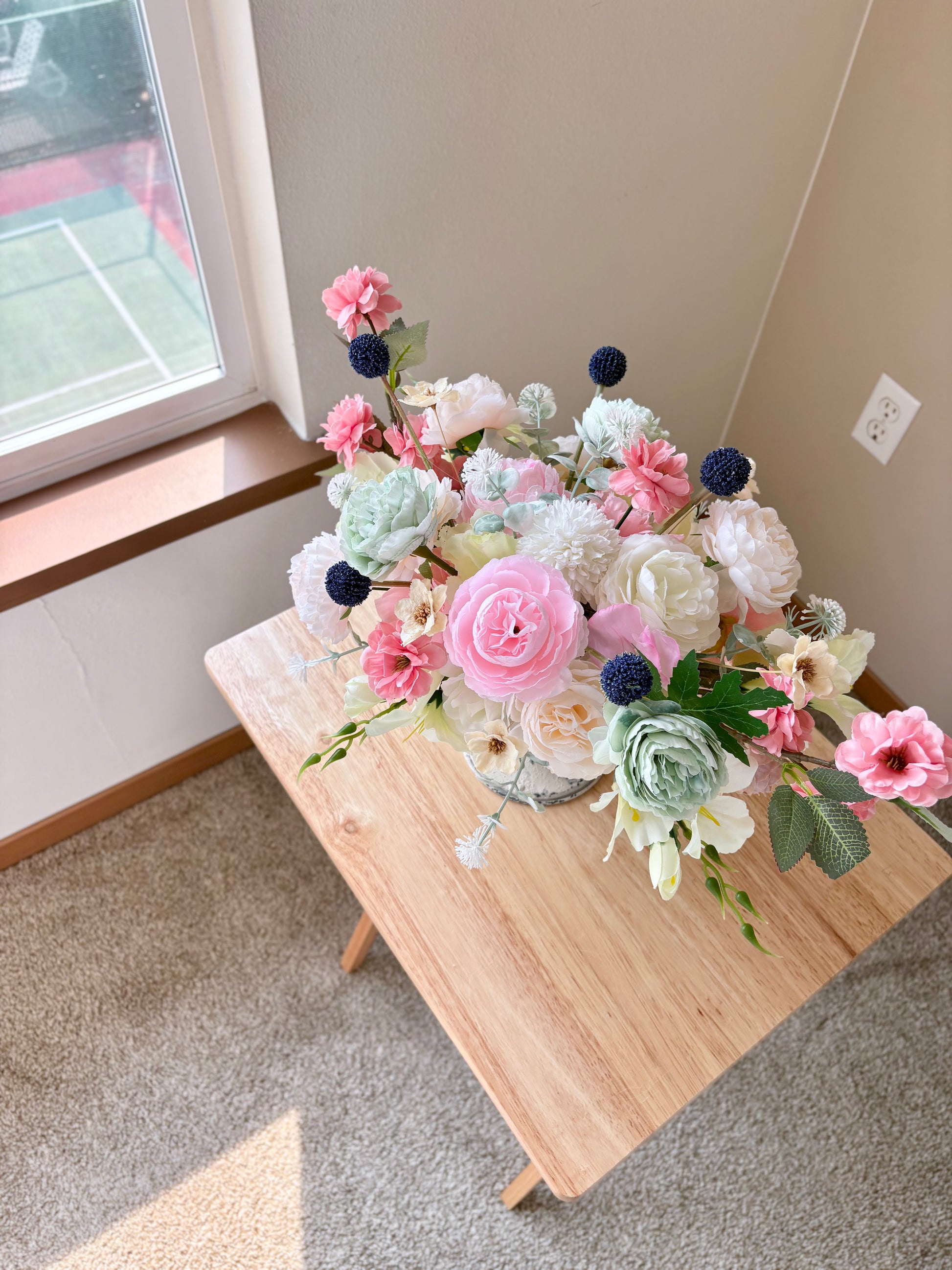 Bouquet of flowers on a wooden table near a window