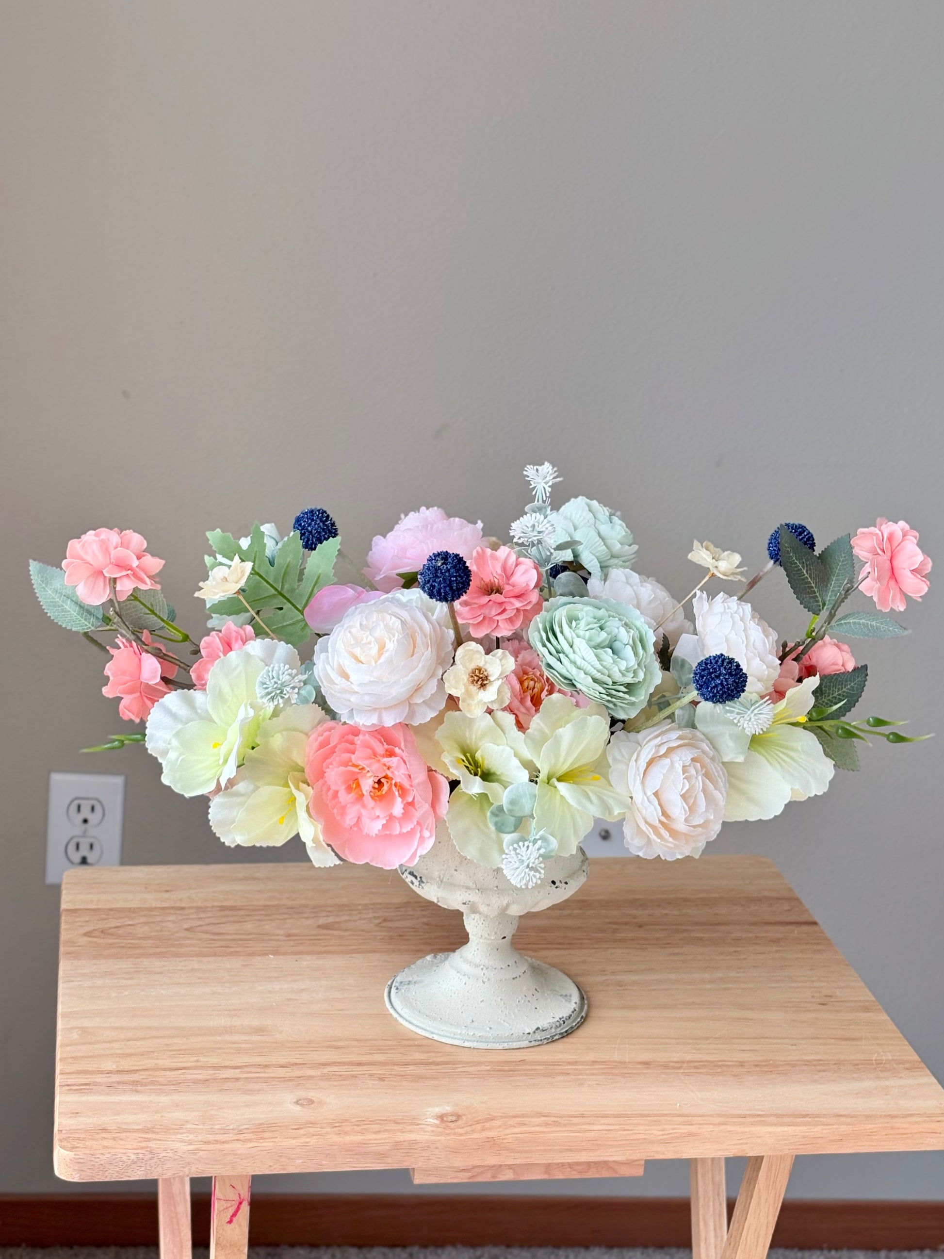 Floral arrangement in a white vase on a wooden table with a neutral background