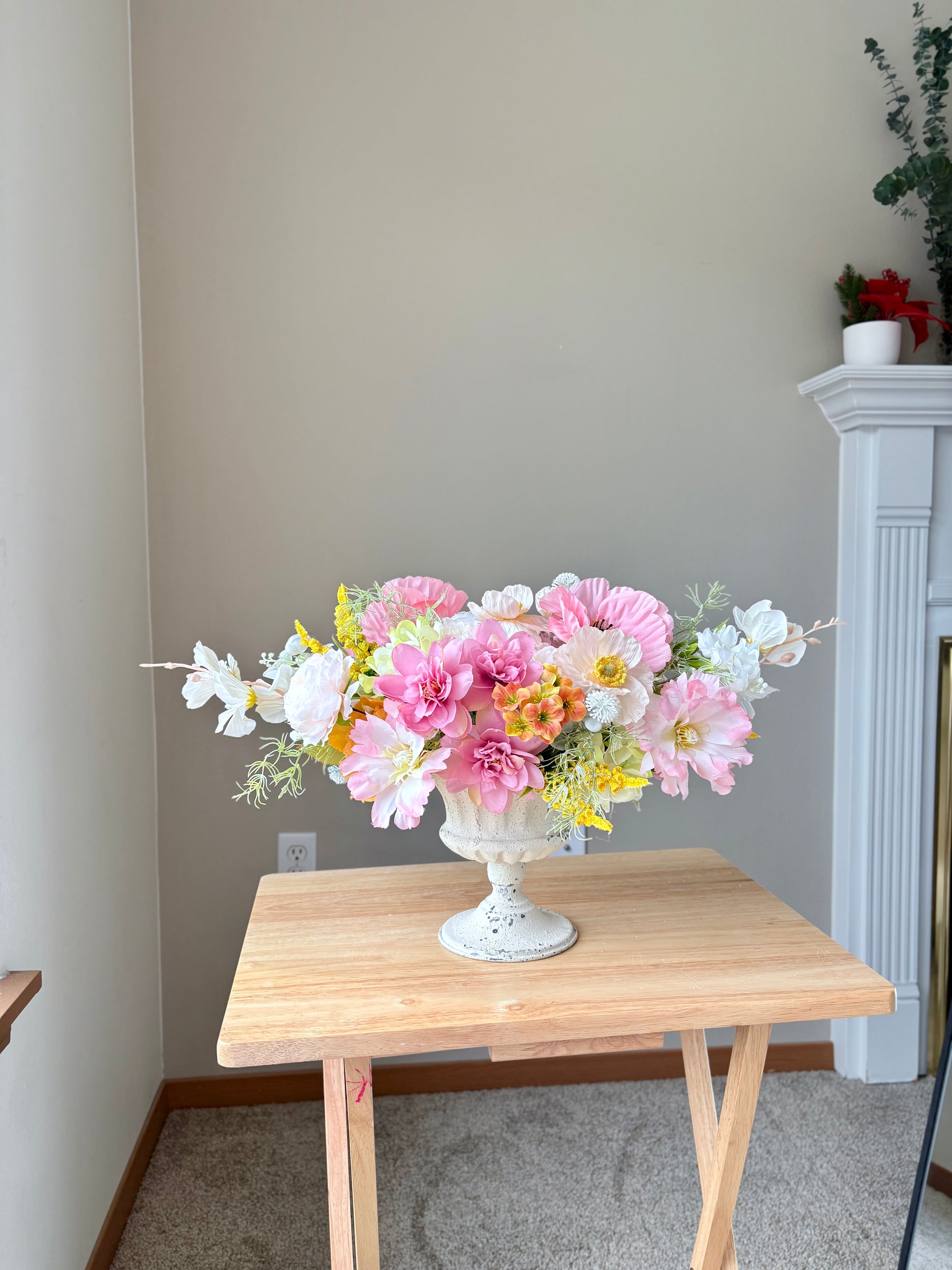 Floral arrangement in a white vase on a wooden table with a neutral background