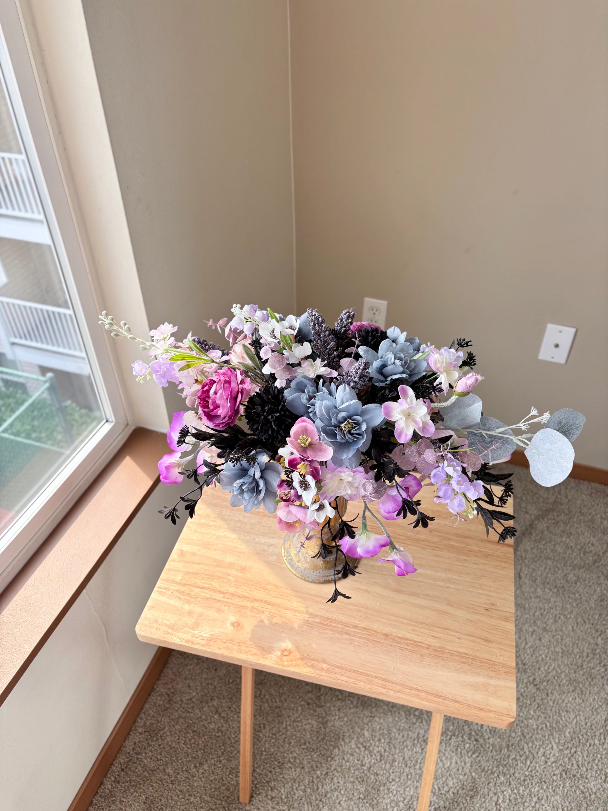 Floral arrangement on a wooden table by a window