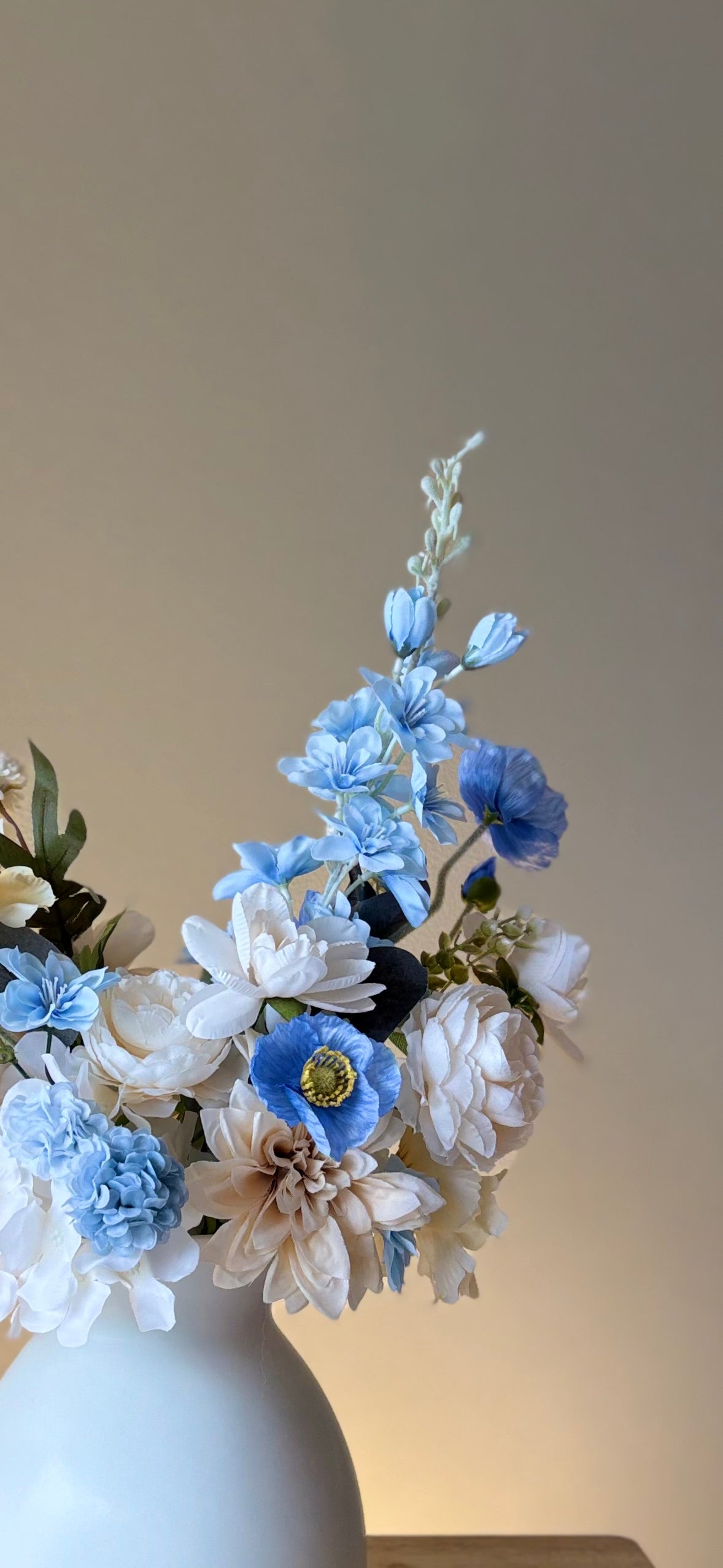 White and blue flowers in a vase against a neutral background