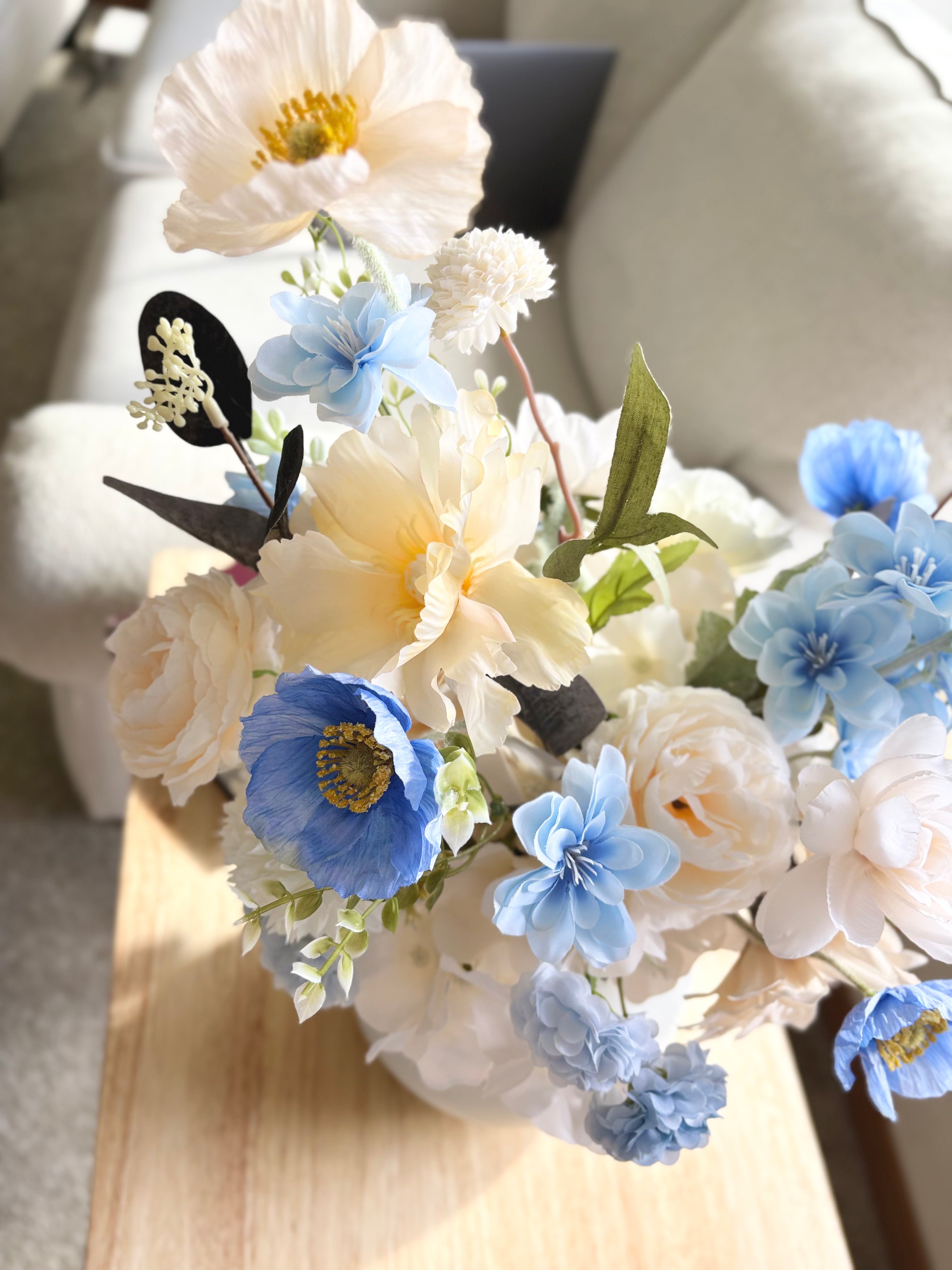 Bouquet of white and blue flowers with butterflies on a wooden surface.
