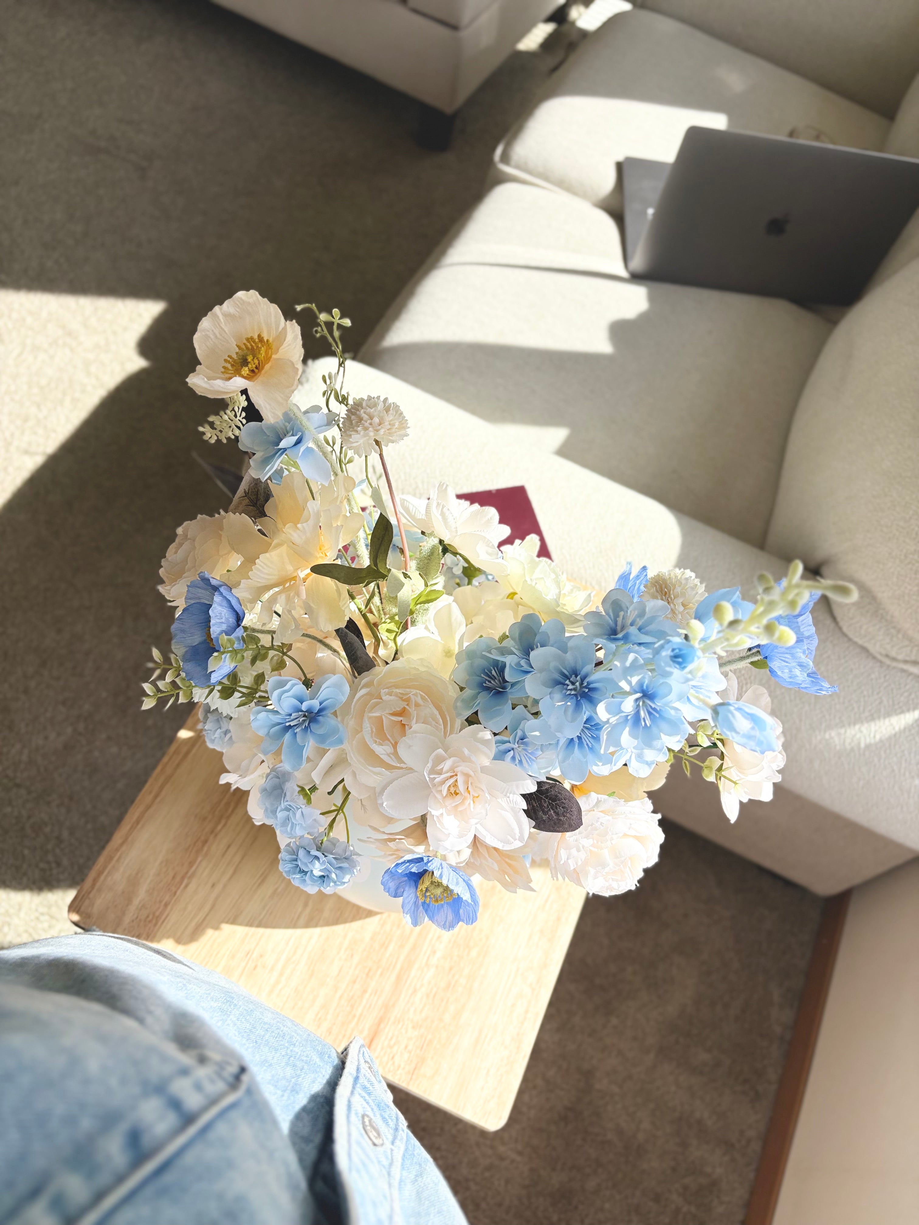 Floral arrangement on a coffee table with a laptop in the background