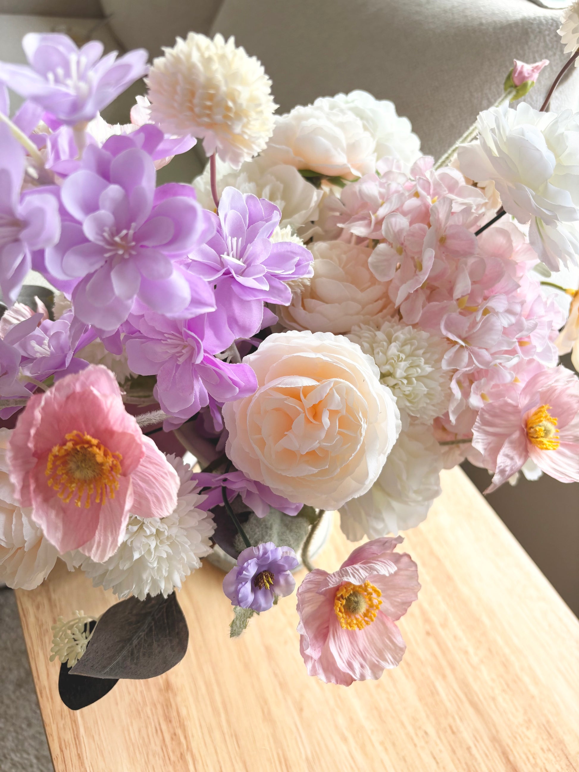 Bouquet of flowers including pink, purple, and white flowers on a wooden surface.