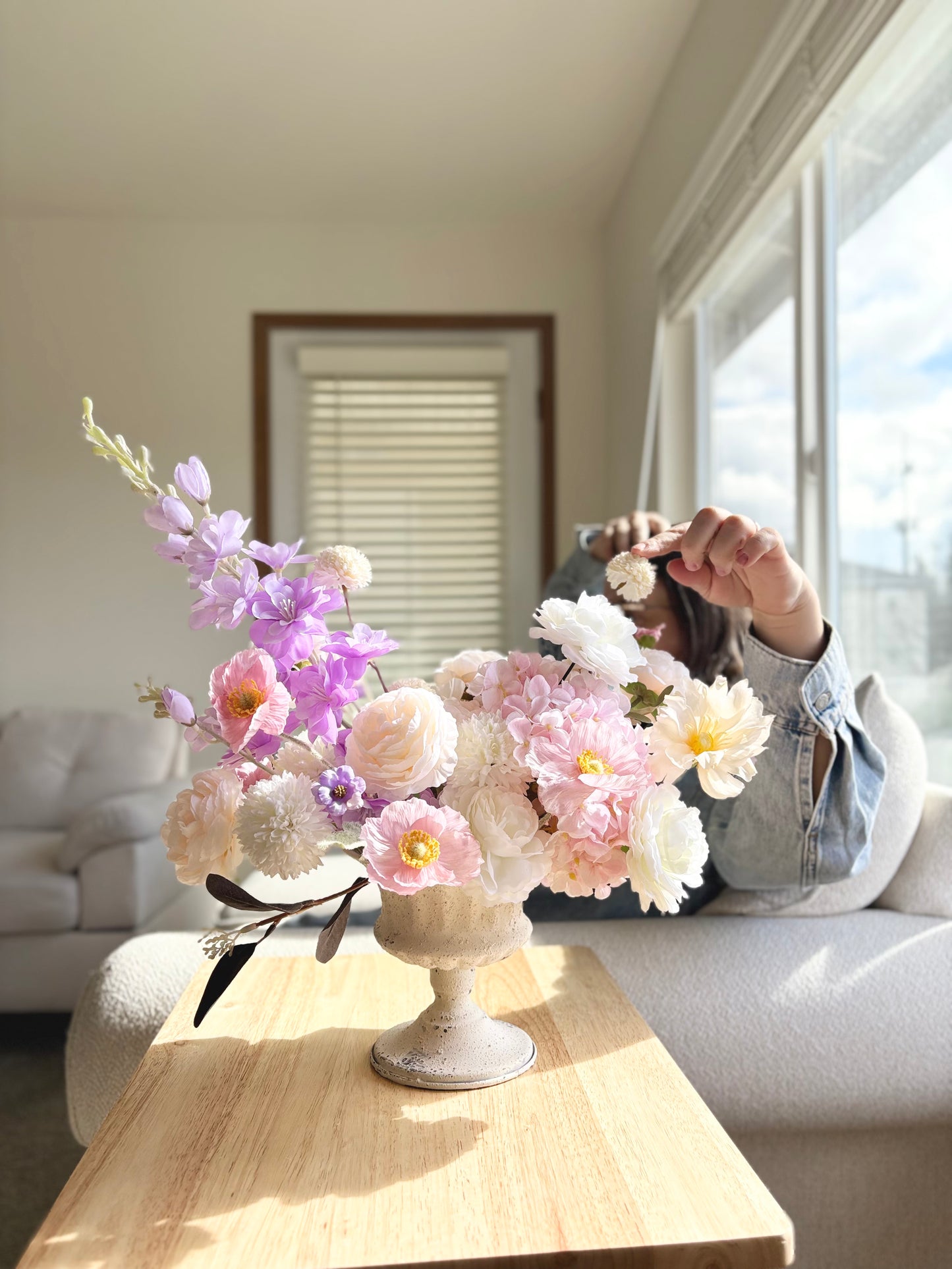 Floral arrangement on a wooden table with a person in the background