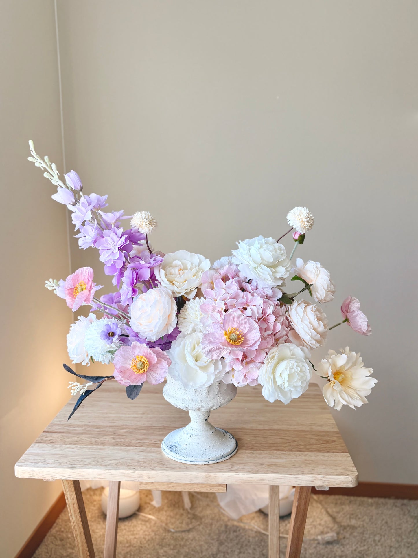 Floral arrangement in a white vase on a wooden table with a neutral background