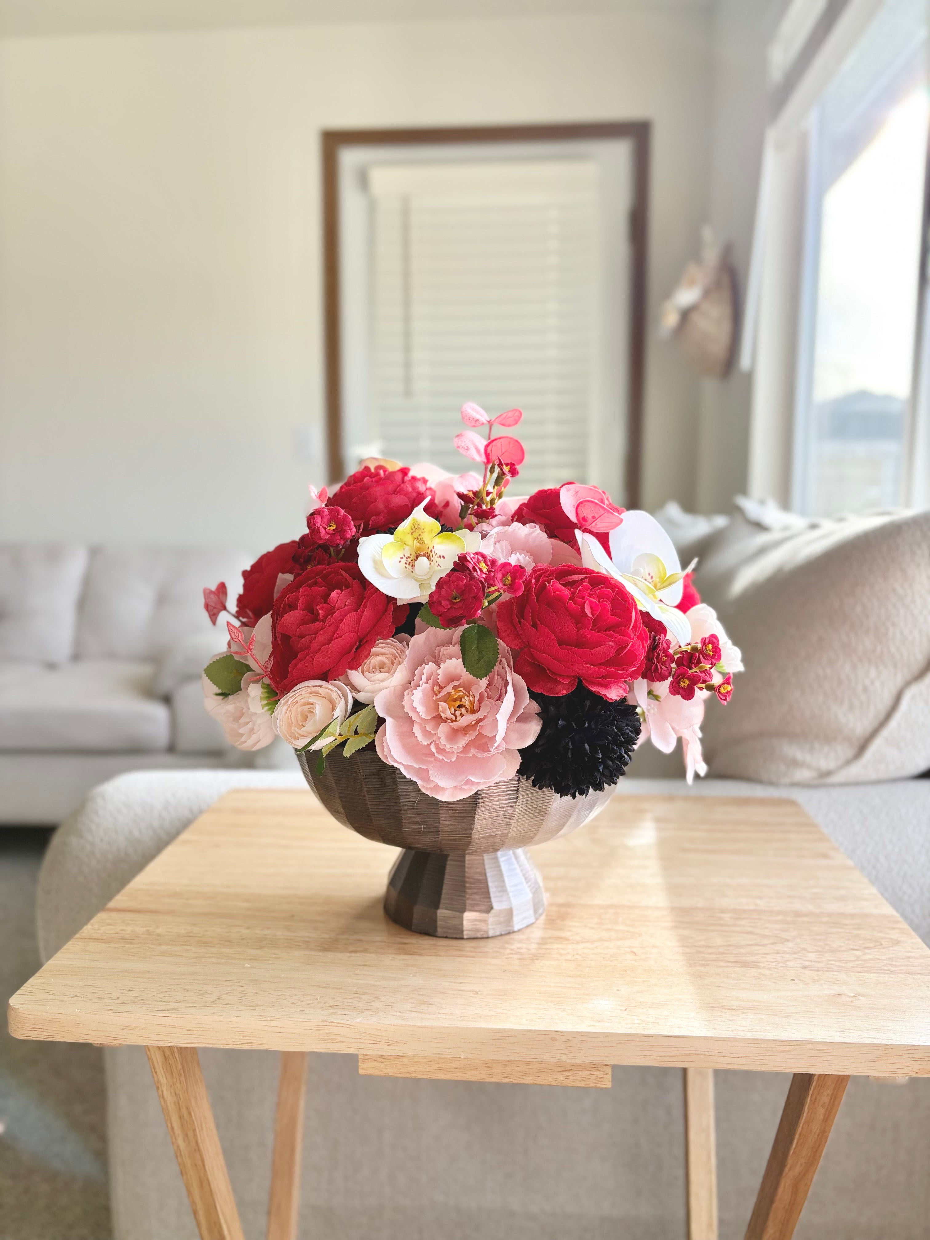 Floral arrangement in a vase on a wooden table in a living room.
