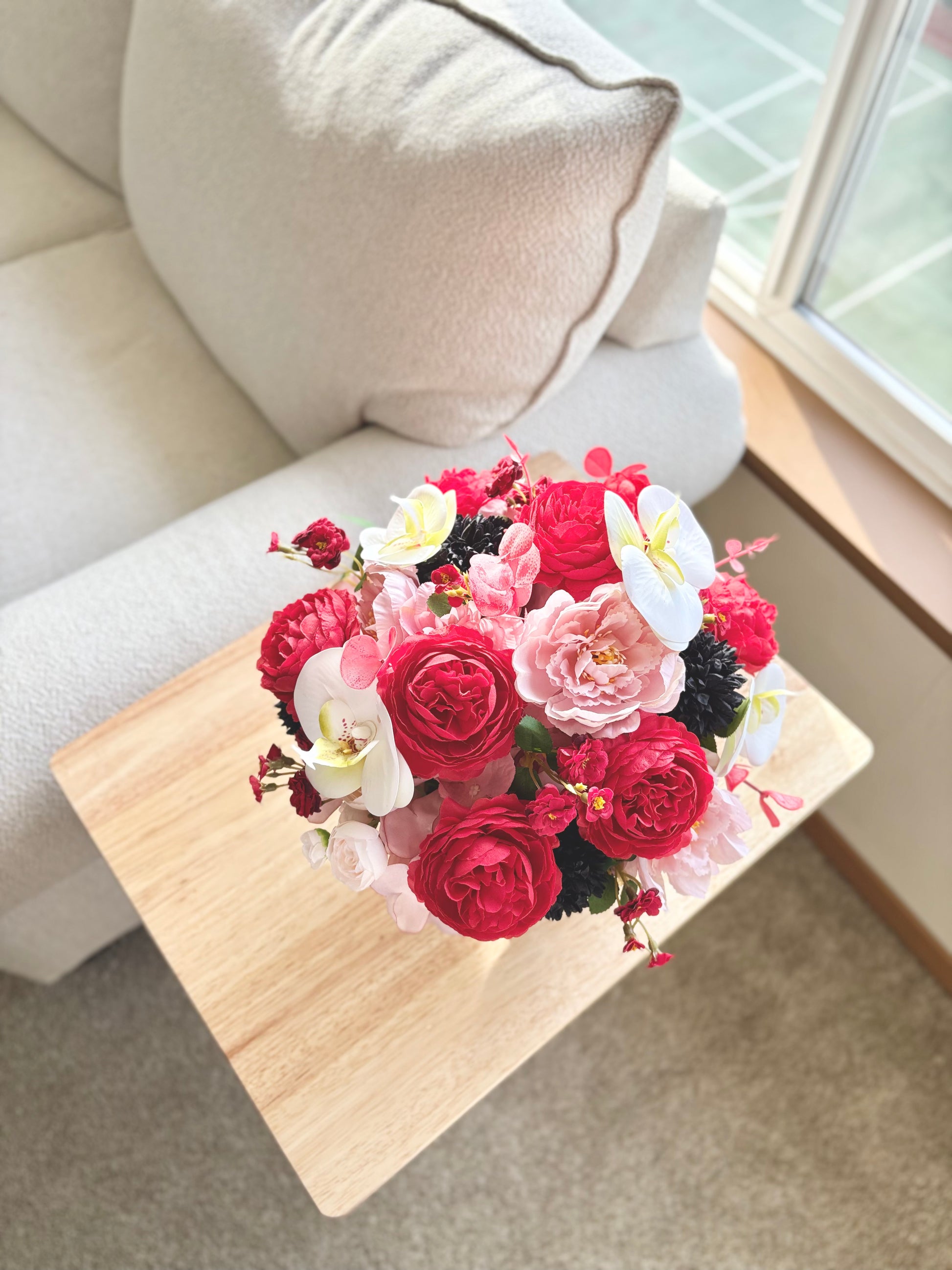 Bouquet of flowers on a small wooden table in a living room setting.