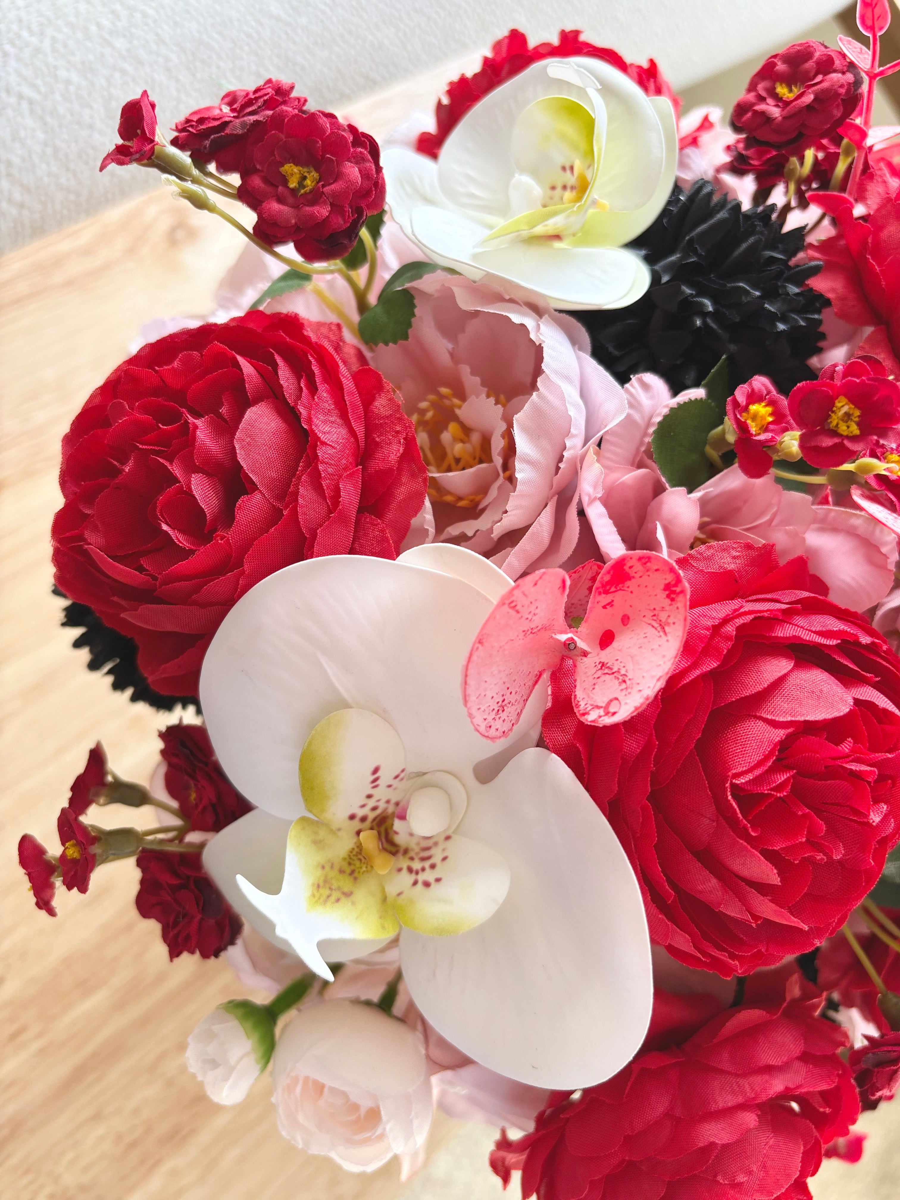 Bouquet of red, pink, and white flowers on a wooden surface
