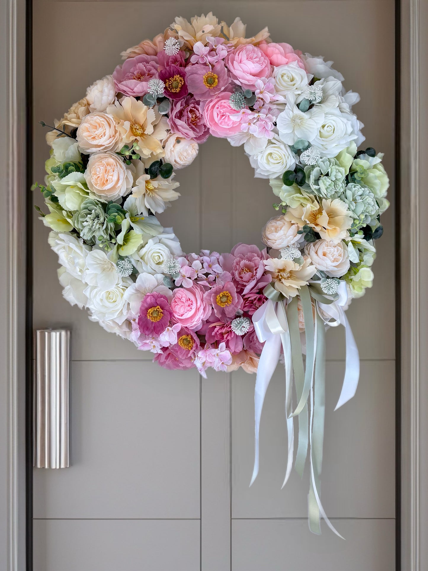 Floral wreath with pink, white, and green flowers on a door