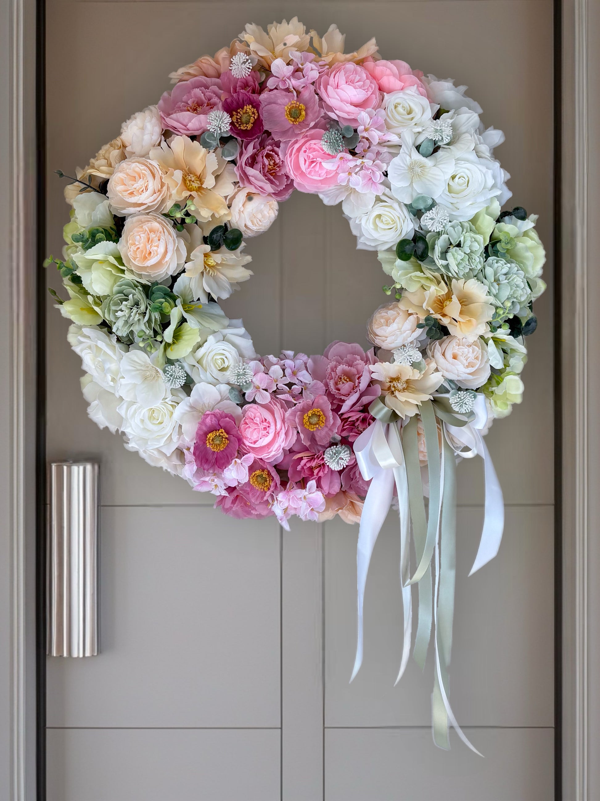 Floral wreath with pink, white, and green flowers on a door