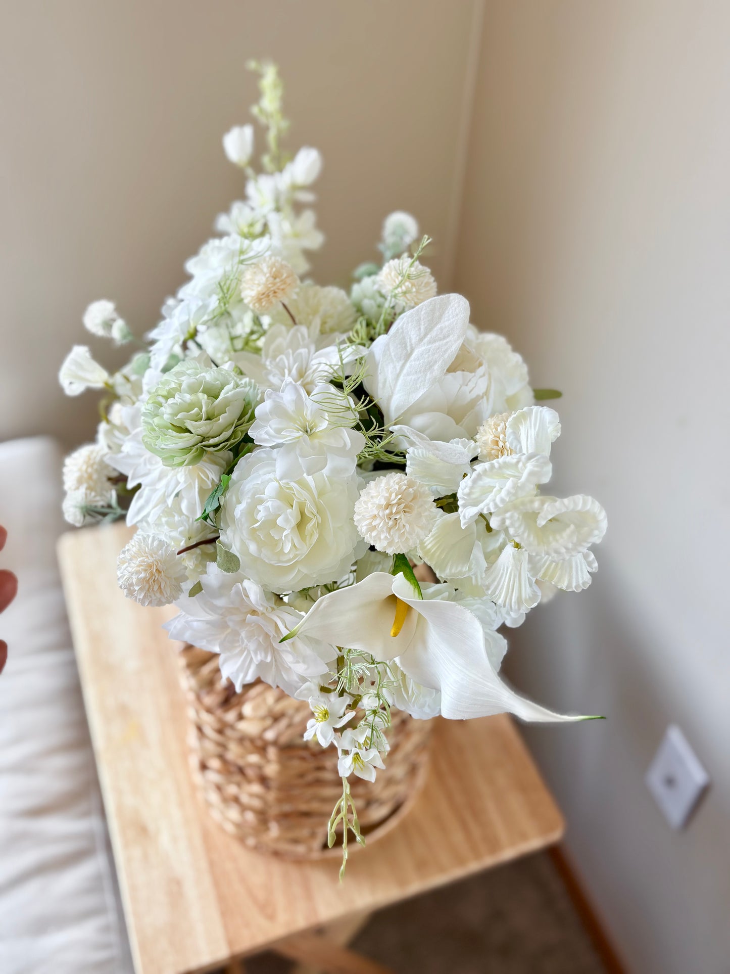 Bouquet of white flowers in a woven basket on a wooden surface.