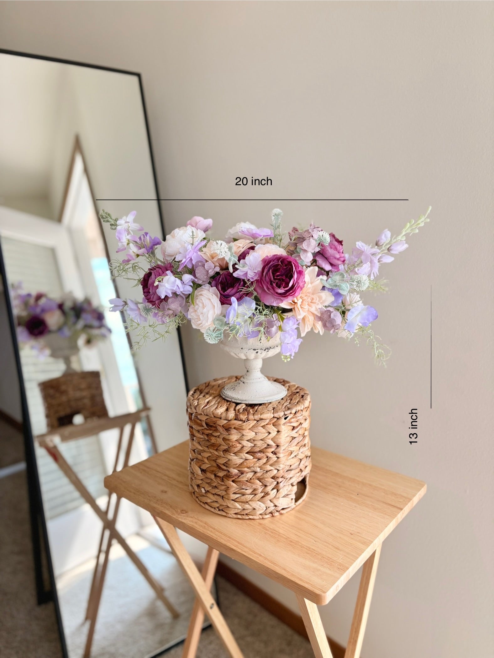 Floral arrangement on a woven stand with dimensions indicated, placed on a wooden table.