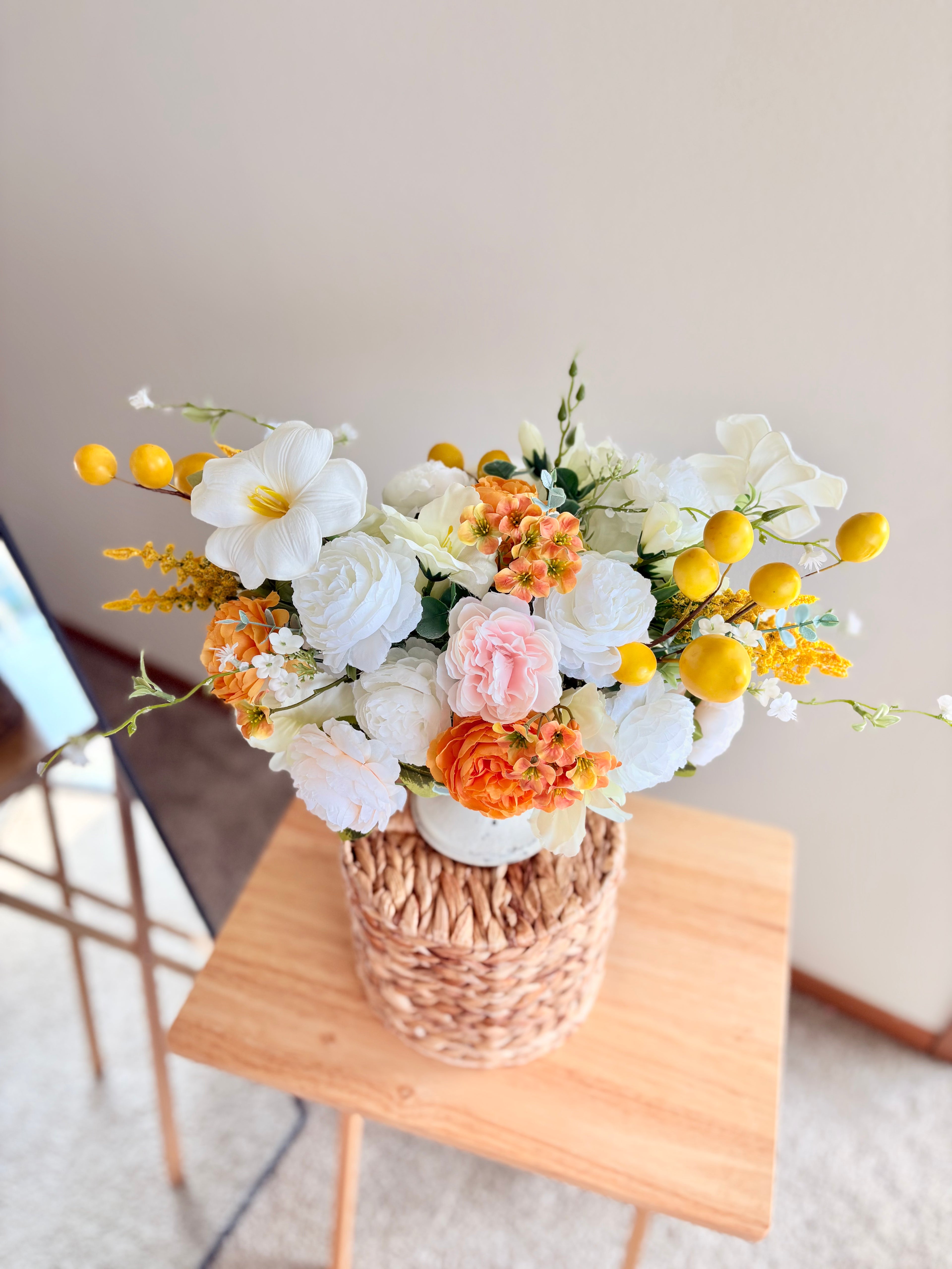 Bouquet of flowers in a woven basket on a wooden table with a neutral background