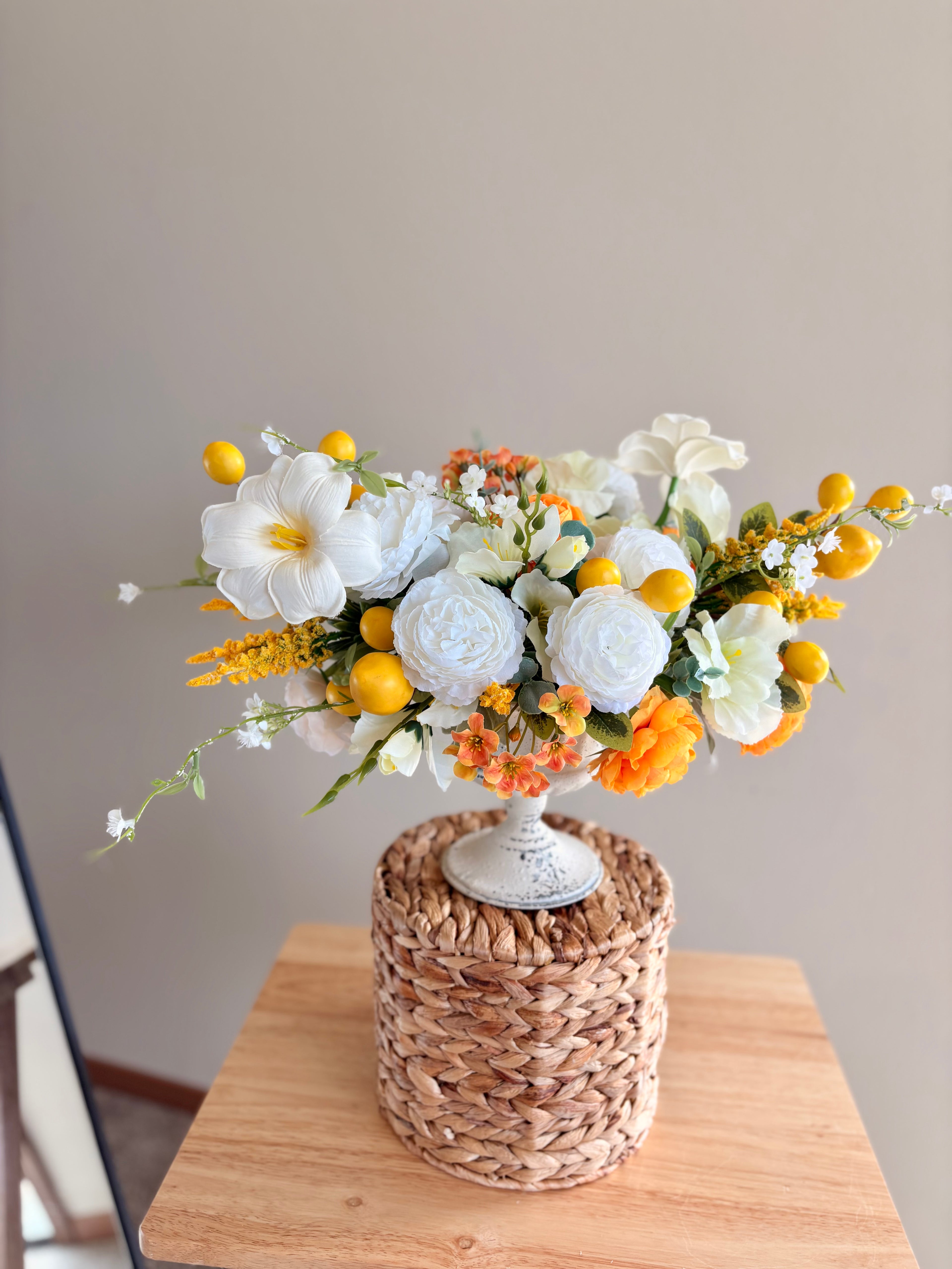 Floral arrangement in a woven basket on a wooden surface with a neutral background