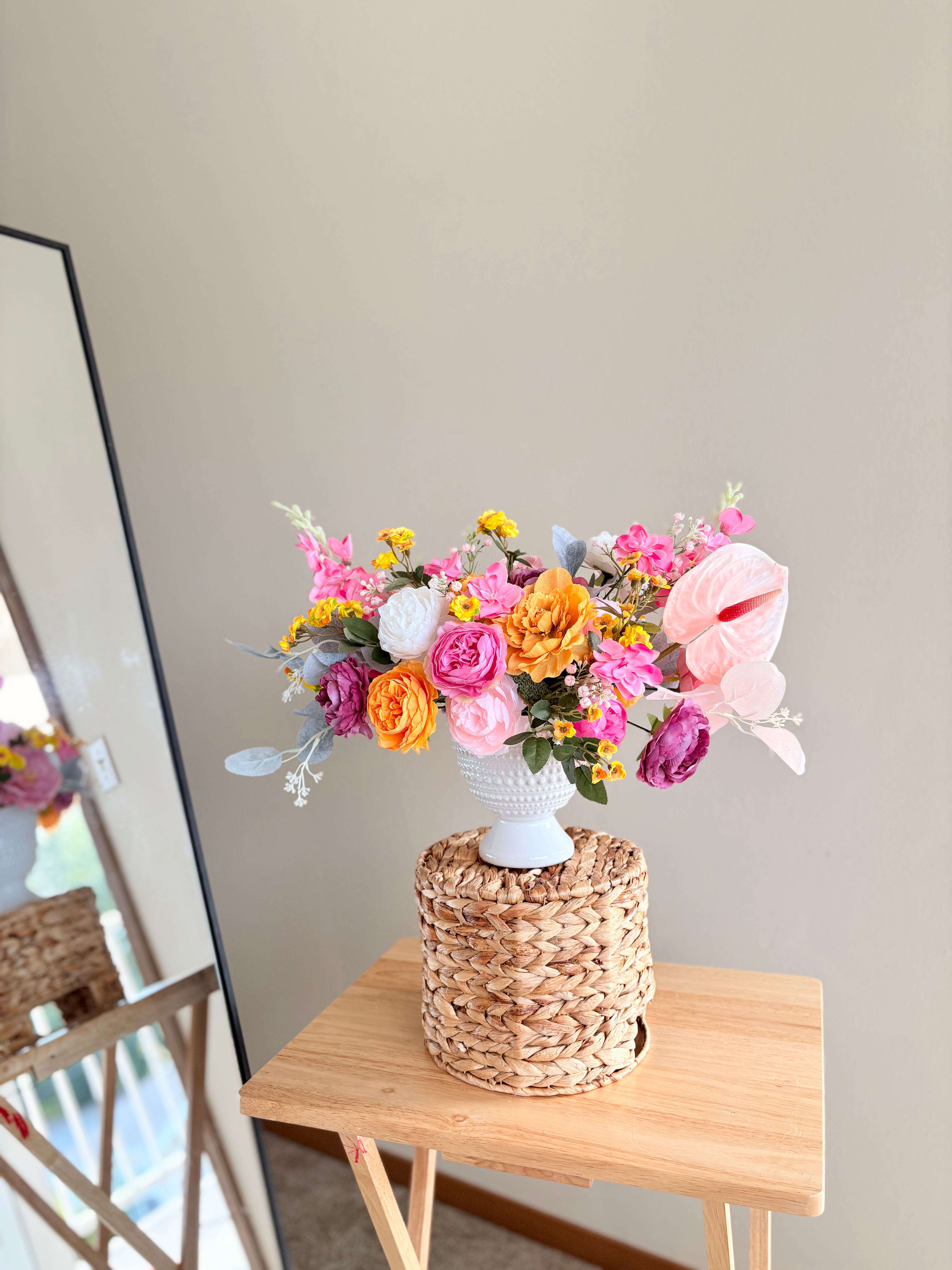 Bouquet of flowers in a woven basket on a wooden table with a neutral background