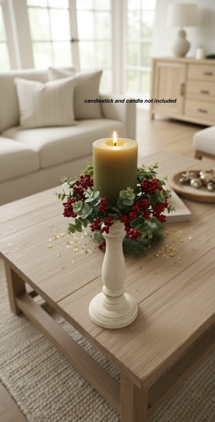 Decorative candle in a white holder on a wooden coffee table with a living room background.