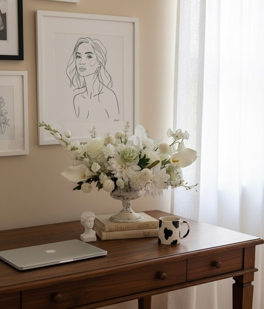 Decorative setup with a laptop, flowers, and books on a wooden desk.