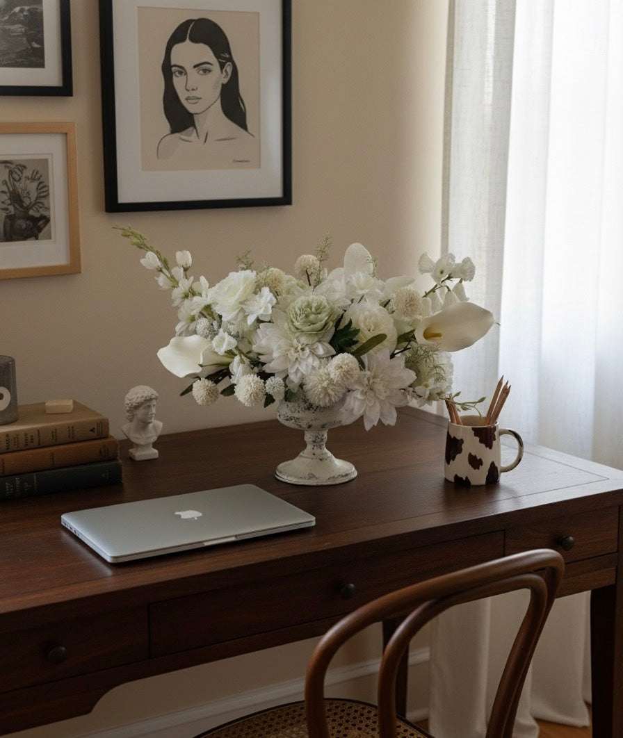 Home office desk with a laptop, flowers, and decorative items.