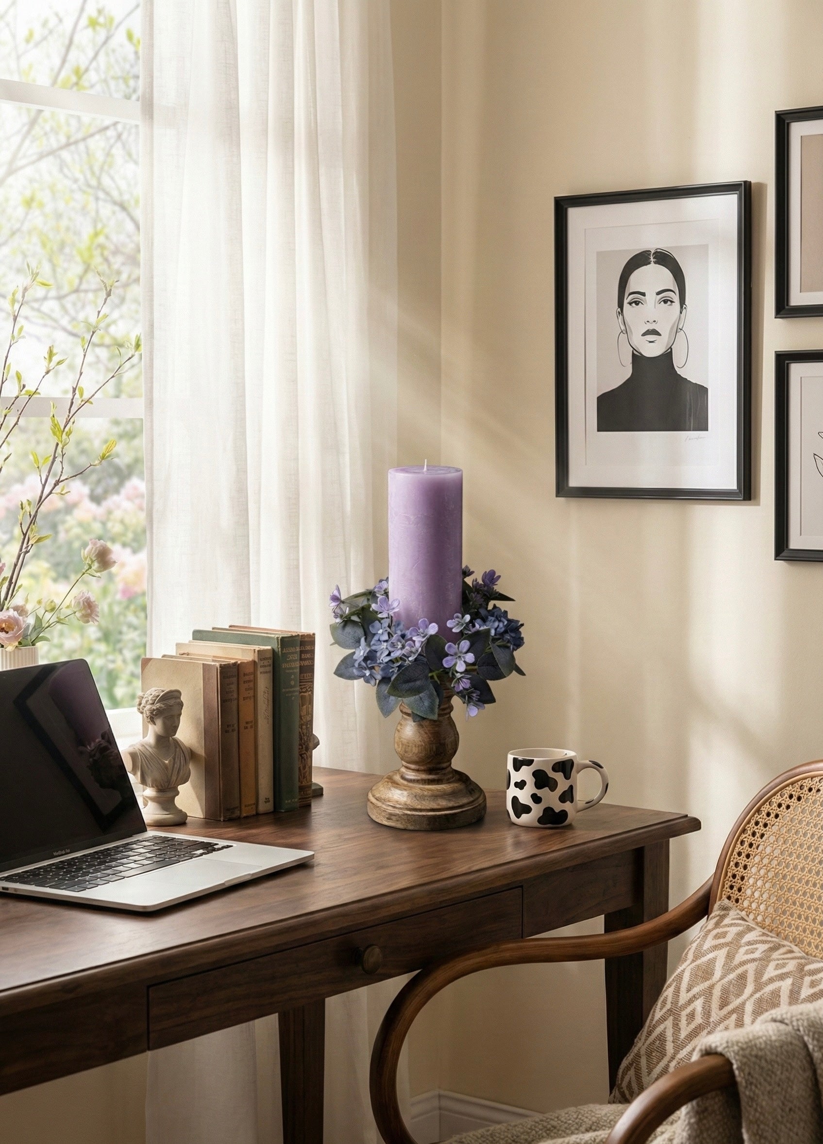 Home office with a desk, laptop, books, candle, and framed picture on a wall.