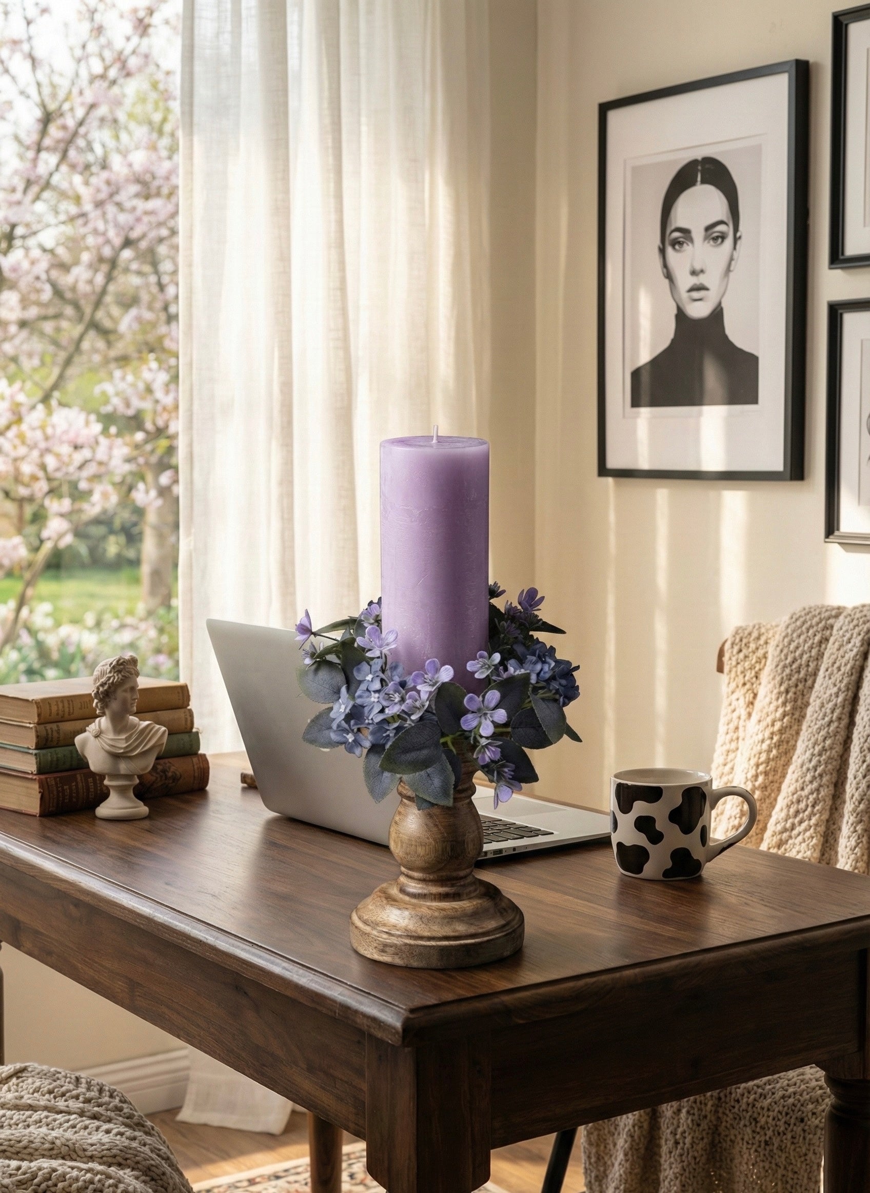 Home office desk with a purple candle, laptop, and decorative items.