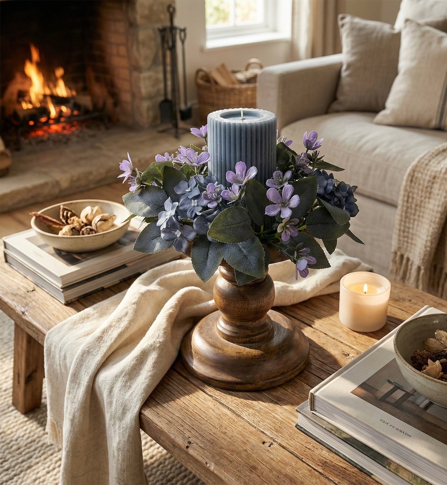 Cozy living room with a wooden table, candle, and floral arrangement.
