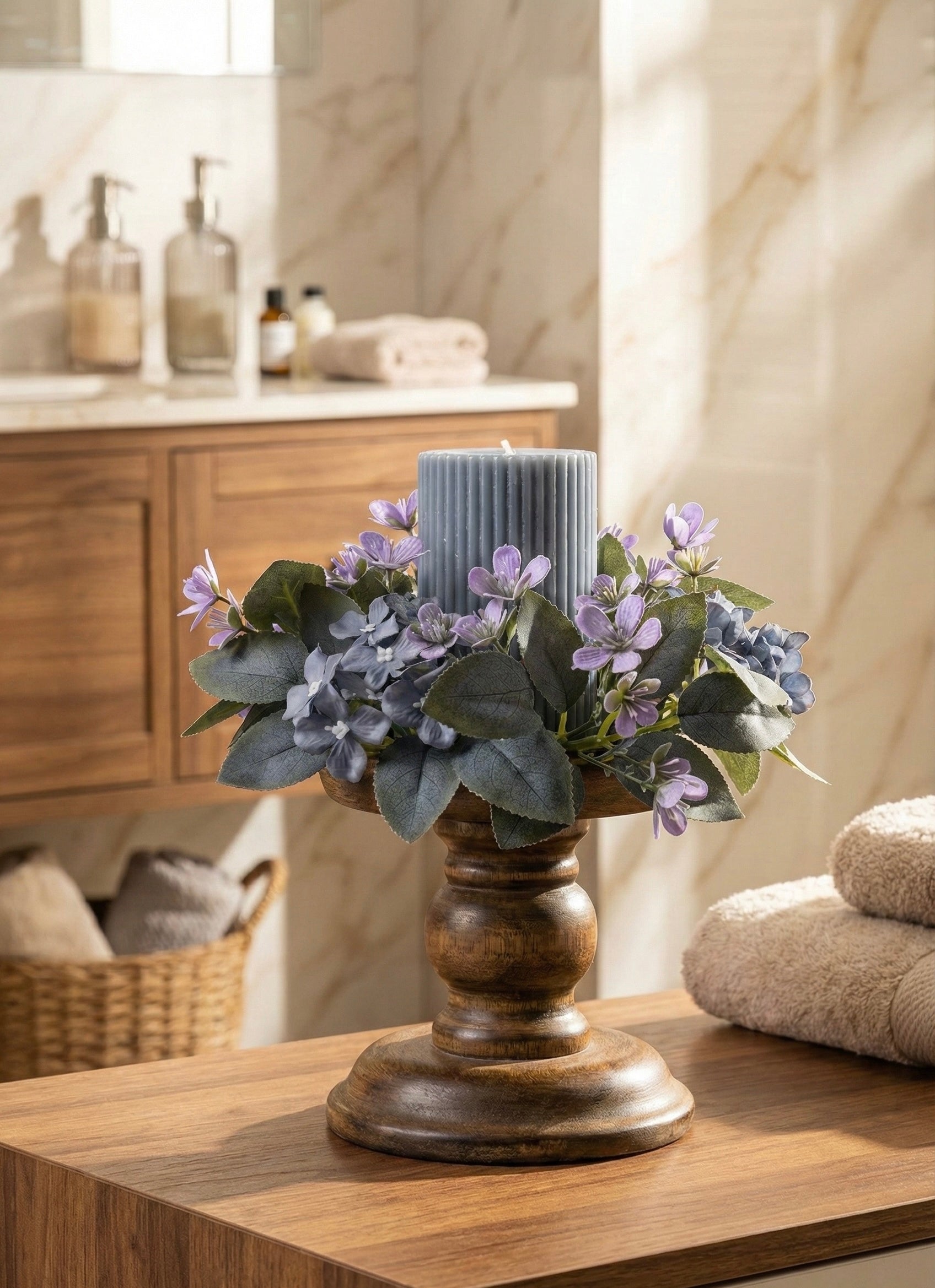 Decorative candle with flowers on a wooden surface in a bathroom setting