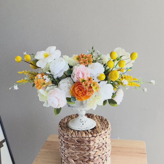 Elegant artificial flower arrangement in a white vase with a mix of white roses, peonies, and delicate orange blossoms accented with bright yellow details. This timeless centerpiece is perfect for year-round home decor, dining table decoration, or as a cheerful gift. Handmade from high-quality faux flowers, it looks realistic, stays fresh all year long, and requires no maintenance. A lovely accent for farmhouse, rustic, or modern interiors.